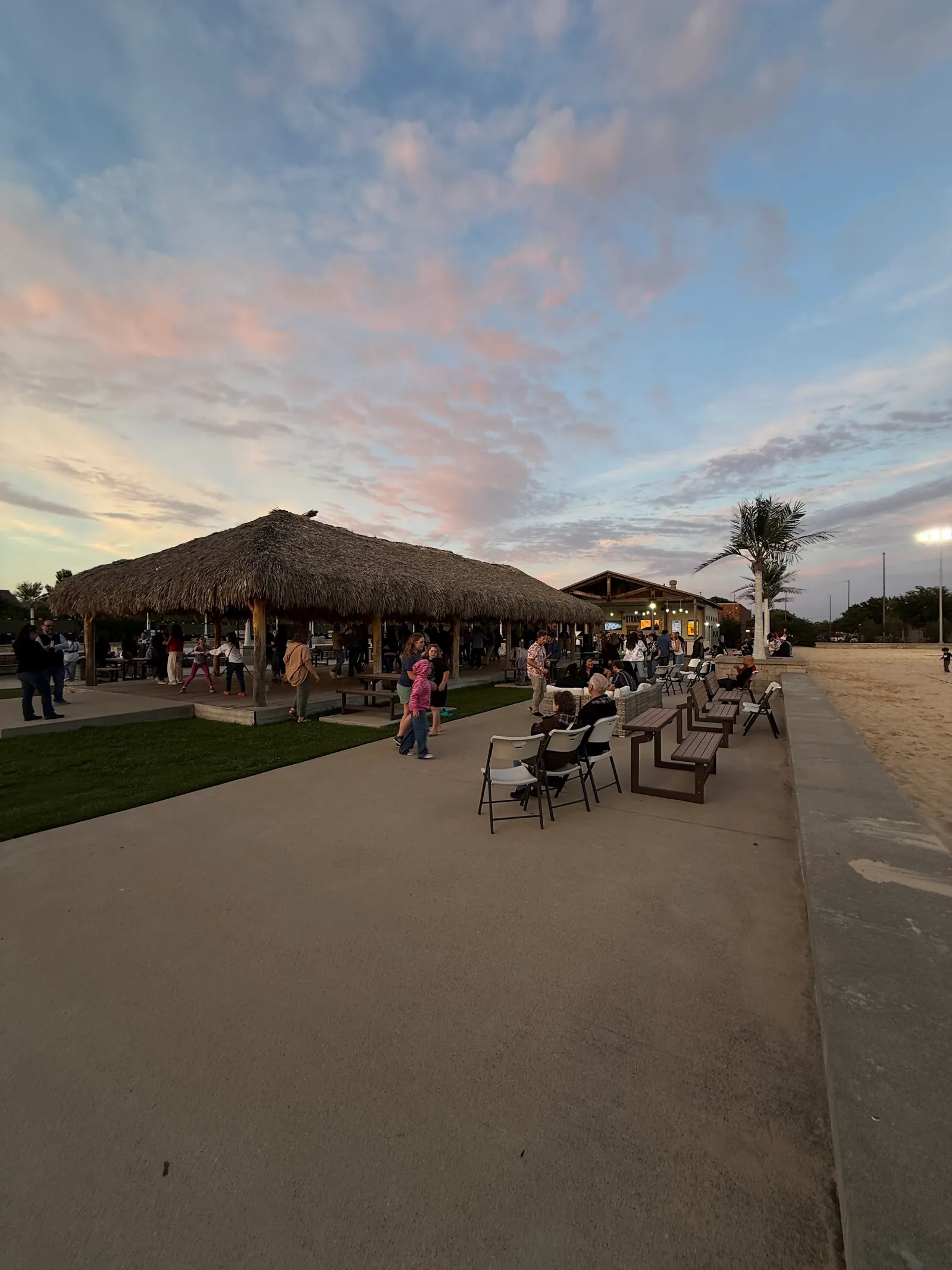 Crowd around the palapa and clubhouse at sunset at The Strand, Lewisville