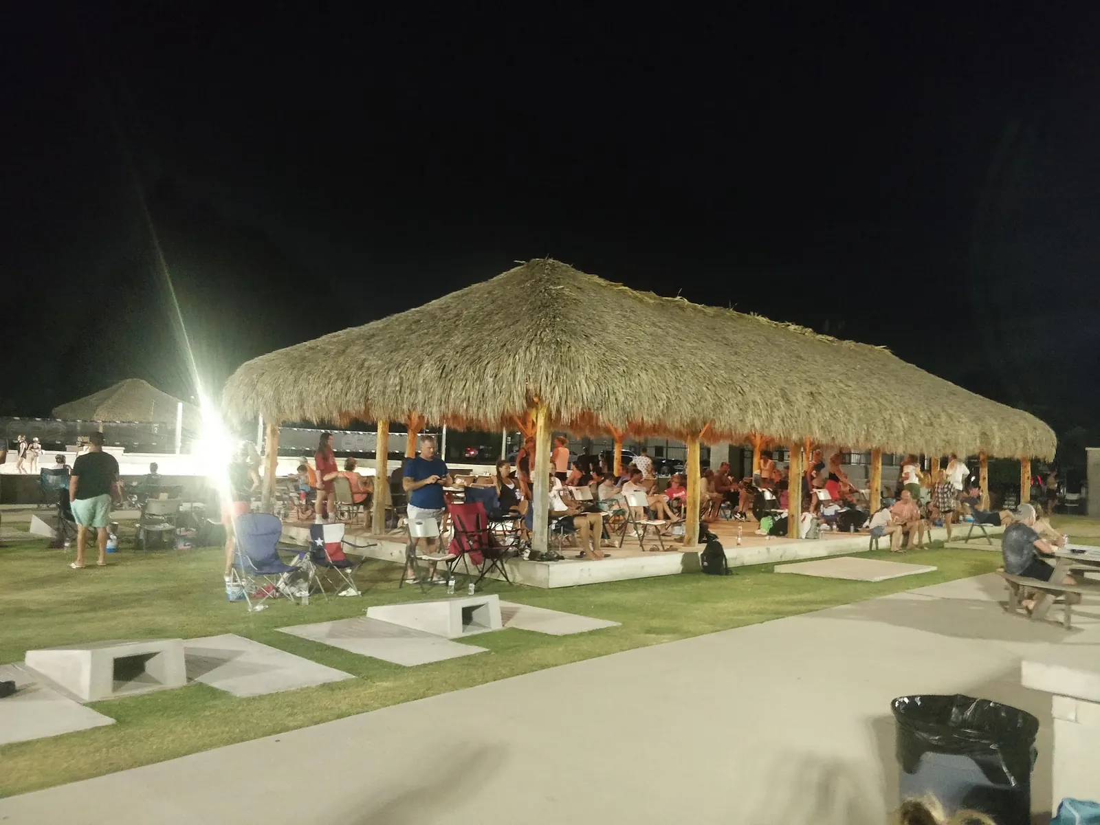 Guests seated under the lit palapa roof at night at The Strand, Lewisville