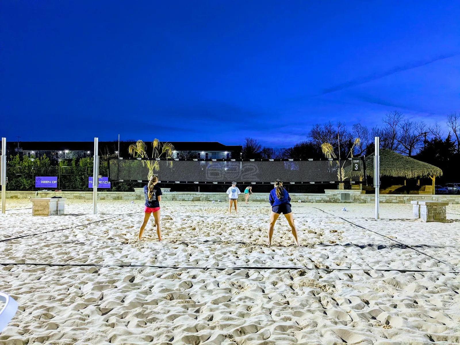 Floodlit sand courts with The Strand banners at night in Lewisville
