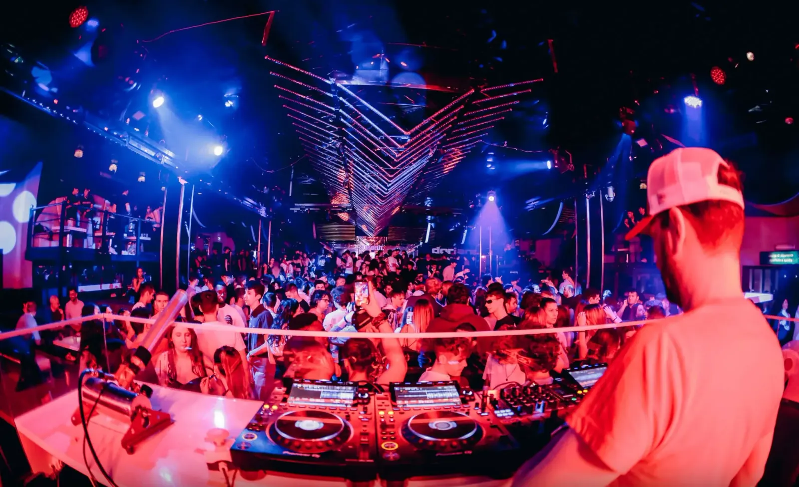 DJ playing to packed dance floor under V-shaped lighting rig at Discoteca Dorian Gray Verona