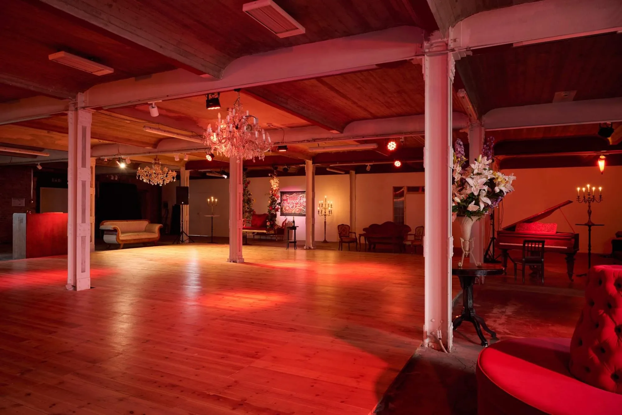 Large red-lit empty dance floor inside Tangoloft Berlin event space