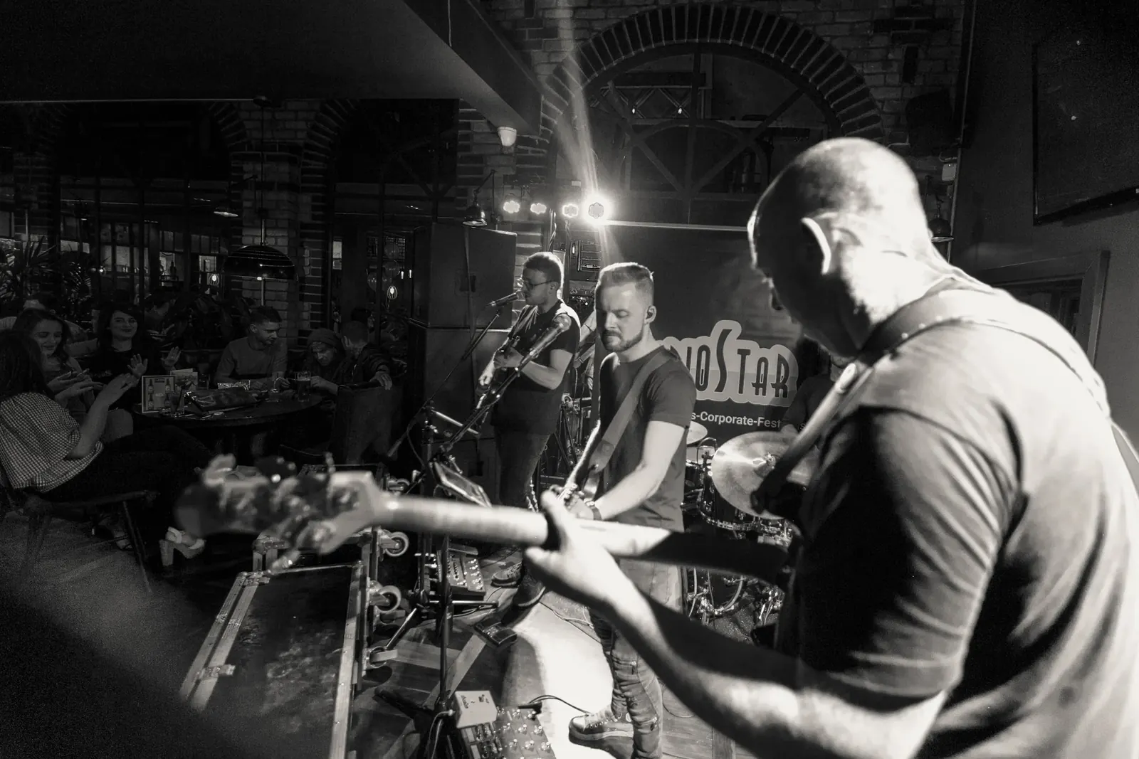 Live band playing guitars and drums to seated guests at Kennys of Lucan, Dublin