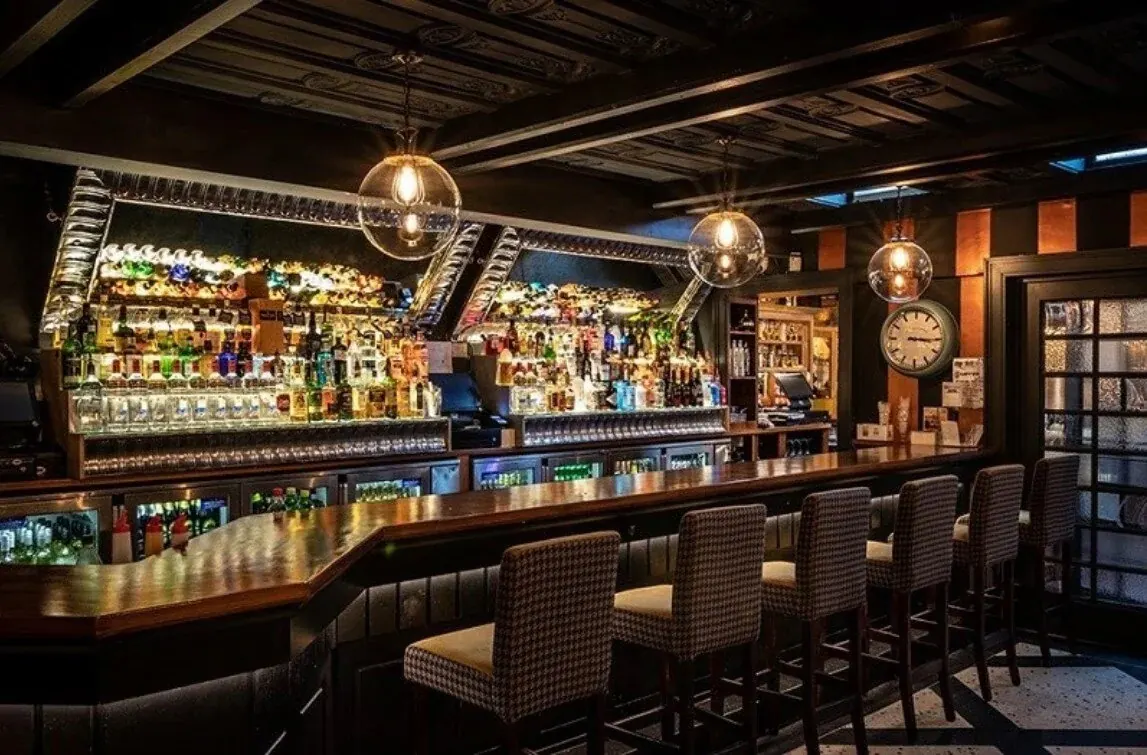 Empty lounge bar with high stools and backlit bottle shelves at Kennys of Lucan