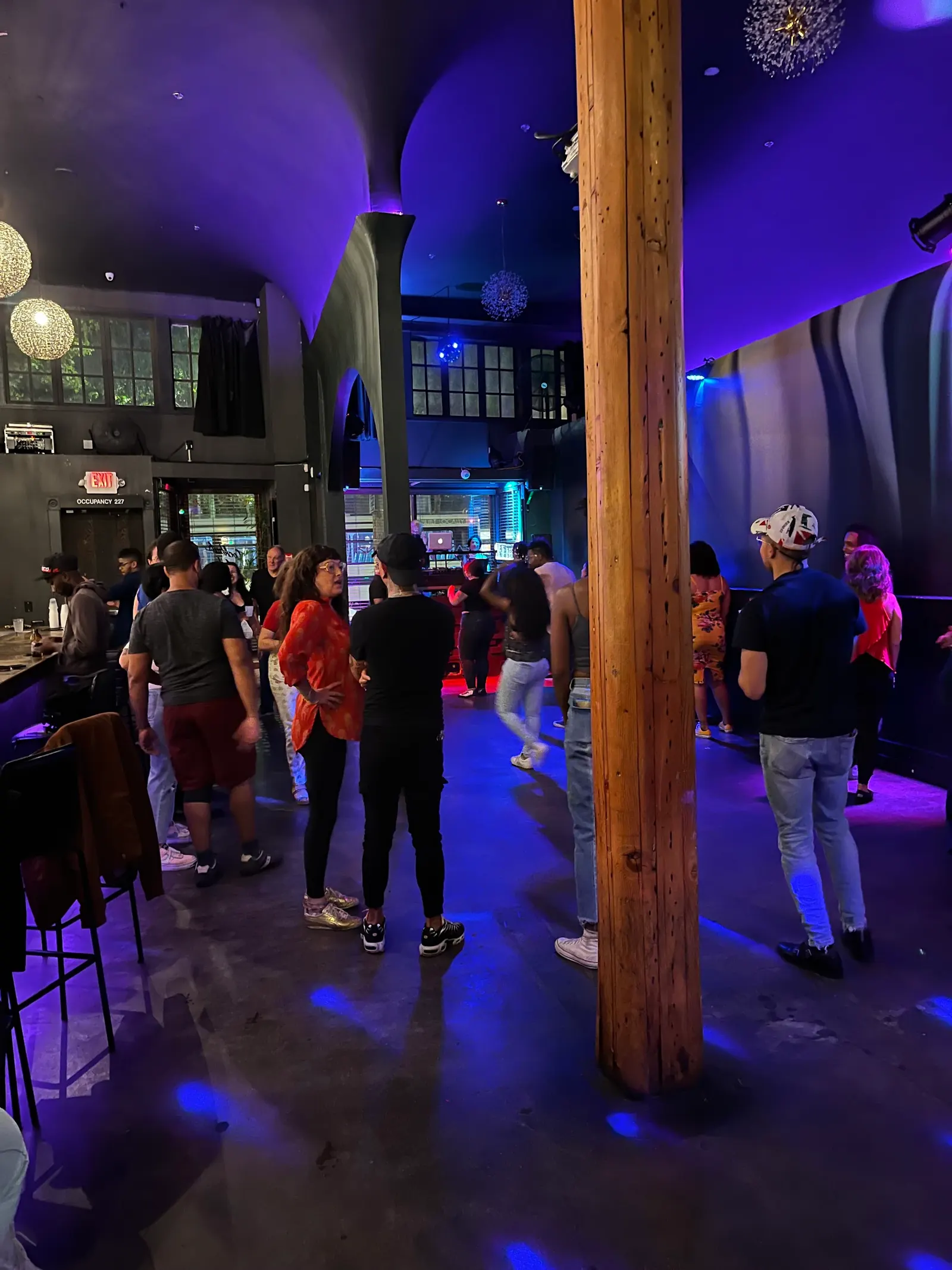 Guests on the purple lit floor by the bar inside Zanzi in Oakland