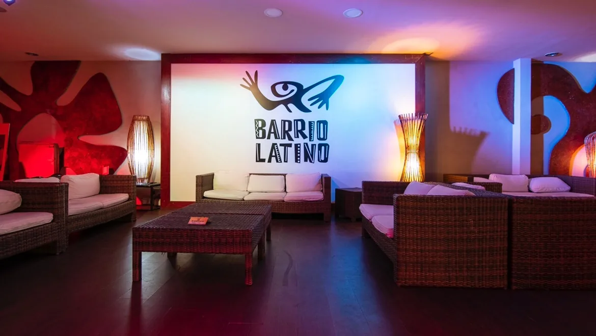Lounge seating area with the Barrio Latino logo wall and club lighting in Rome