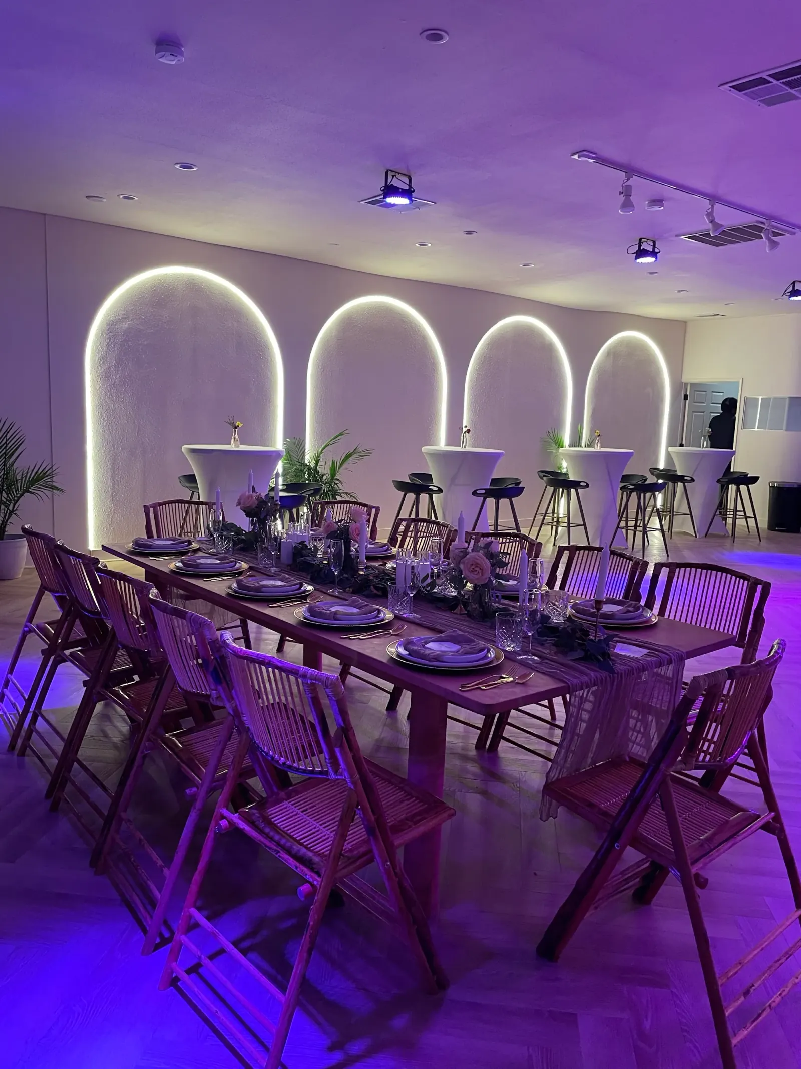 Event hall at Little Light Venue with illuminated arch features, long dinner table and purple lighting