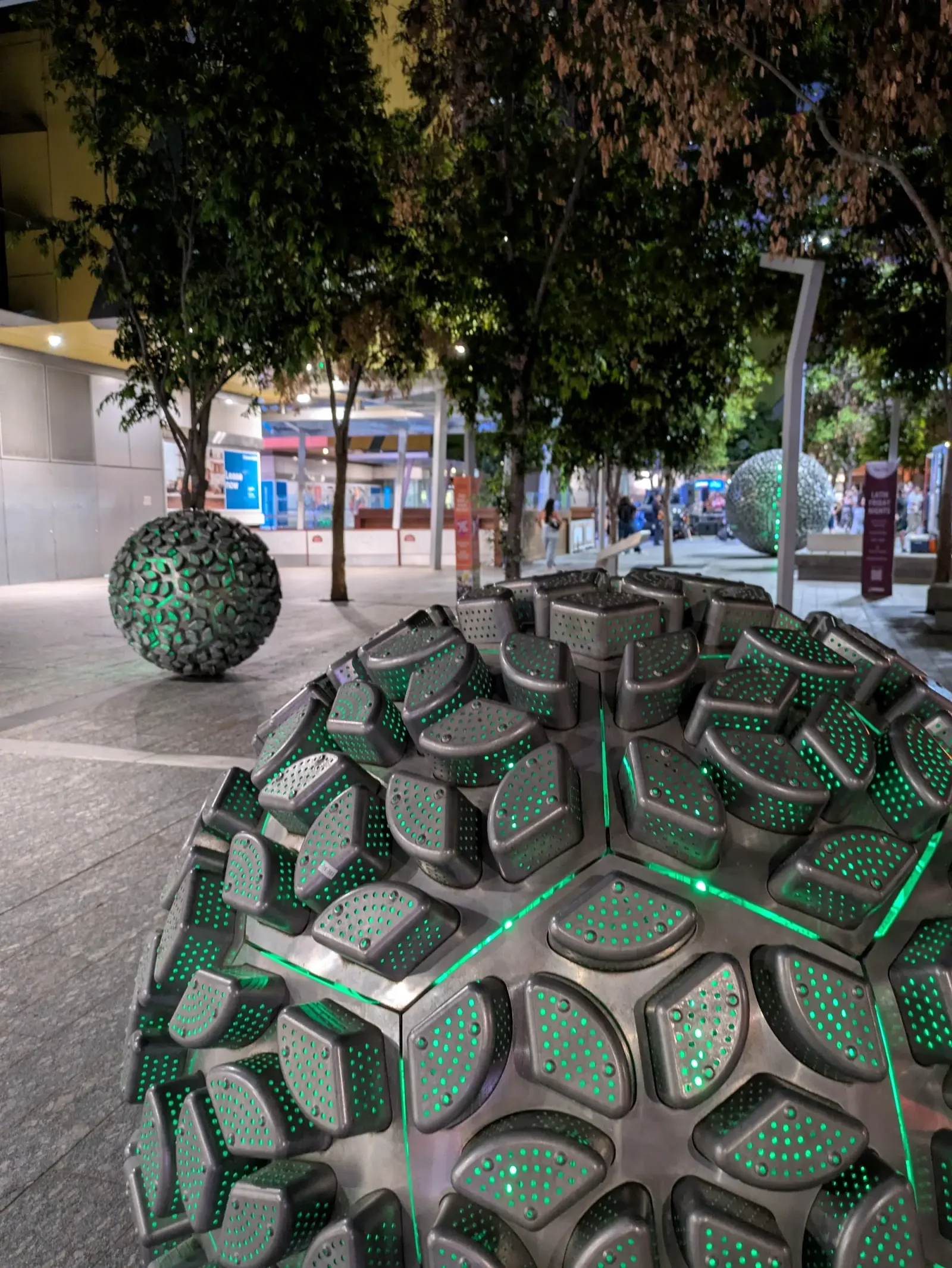 Reddacliff Place Brisbane at night — sphere sculptures lit with green LEDs and trees in background