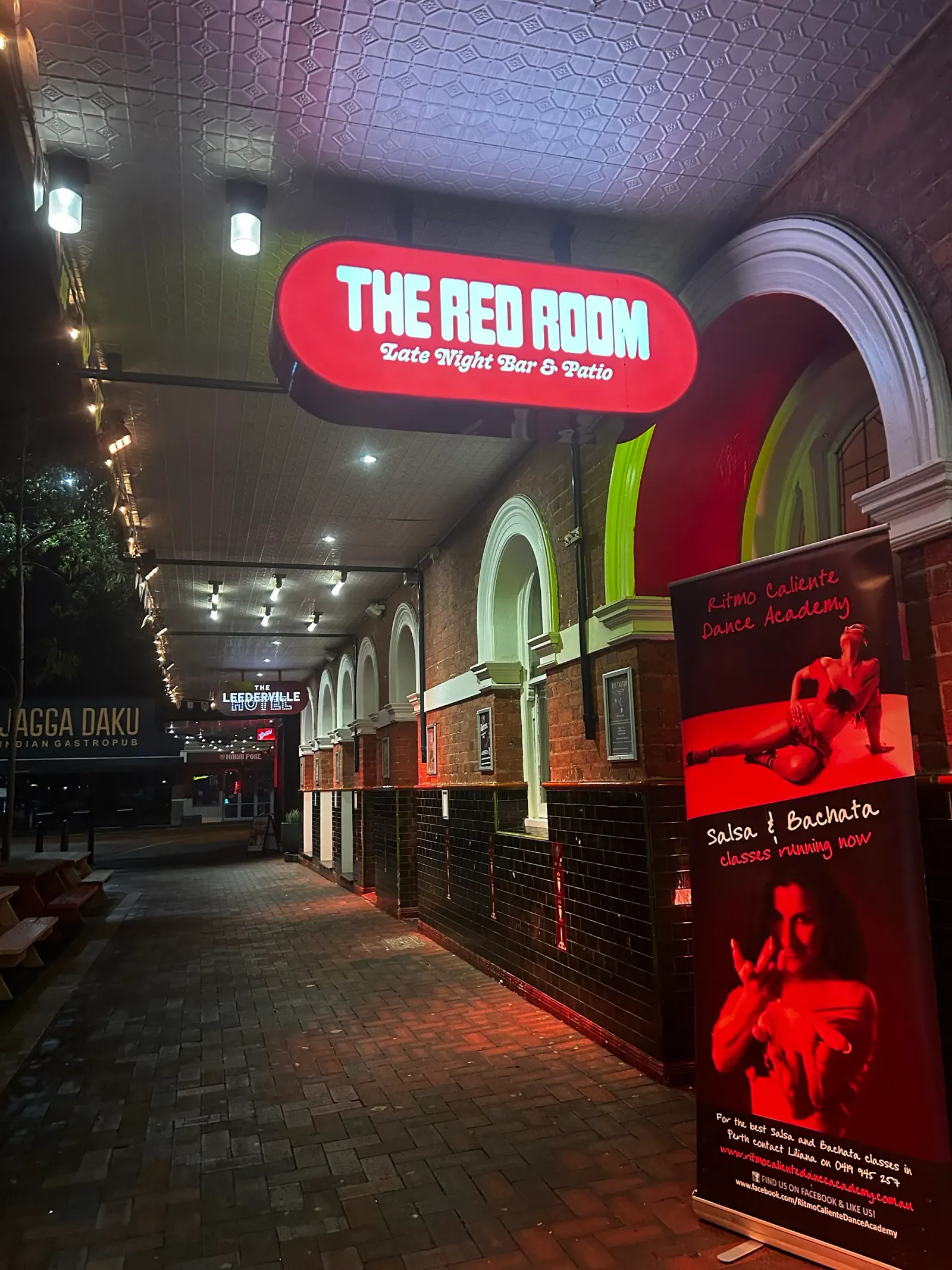 The Red Room Late Night Bar entrance at night with Ritmo Caliente Dance Academy Salsa and Bachata banner