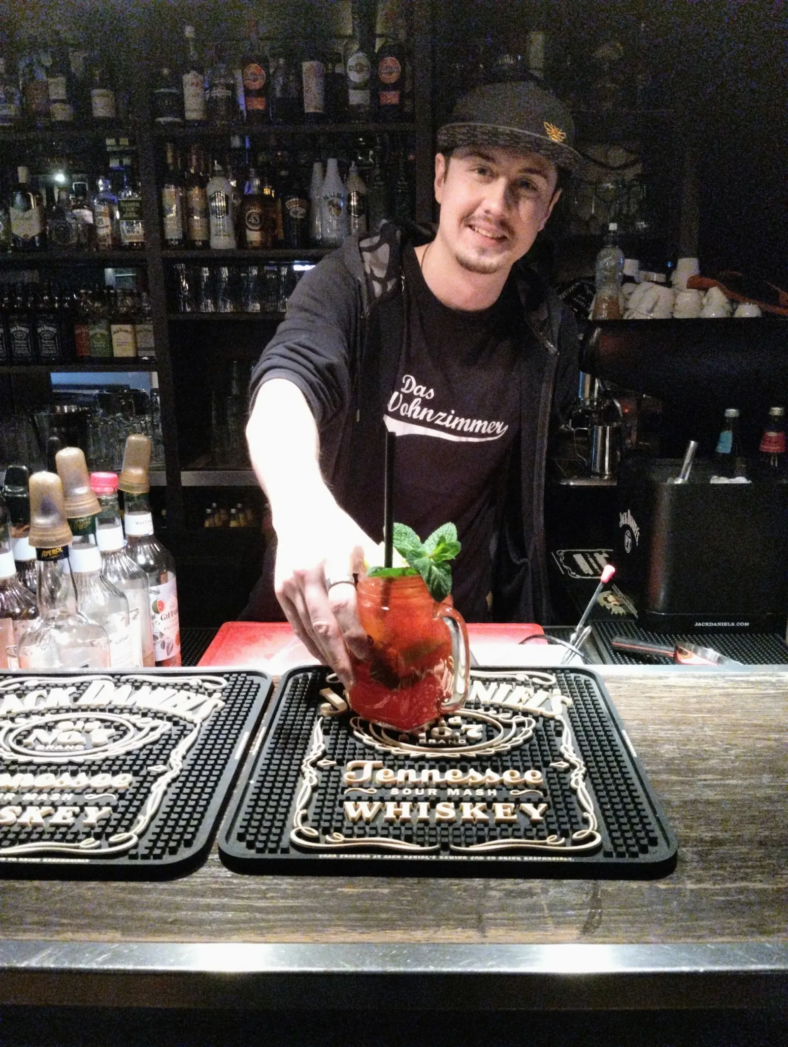 Bartender in branded shirt mixing a cocktail at the bar of Das Wohnzimmer in Wiesbaden