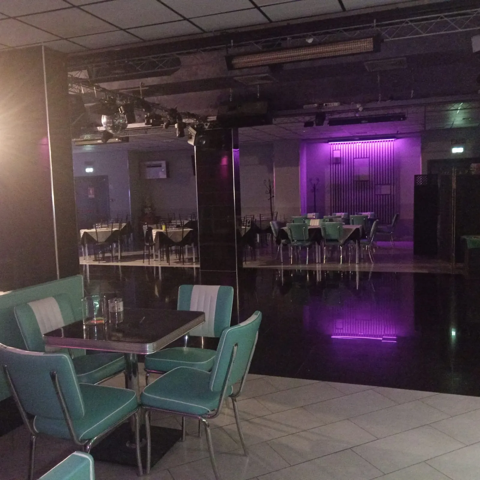PERUNQUE interior — dance hall with mirror walls, seating booths and reflective dance floor under purple lighting