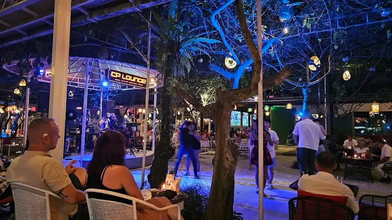 People dancing at CP Lounge Bali outdoor venue with live band on stage and blue stage lighting at night