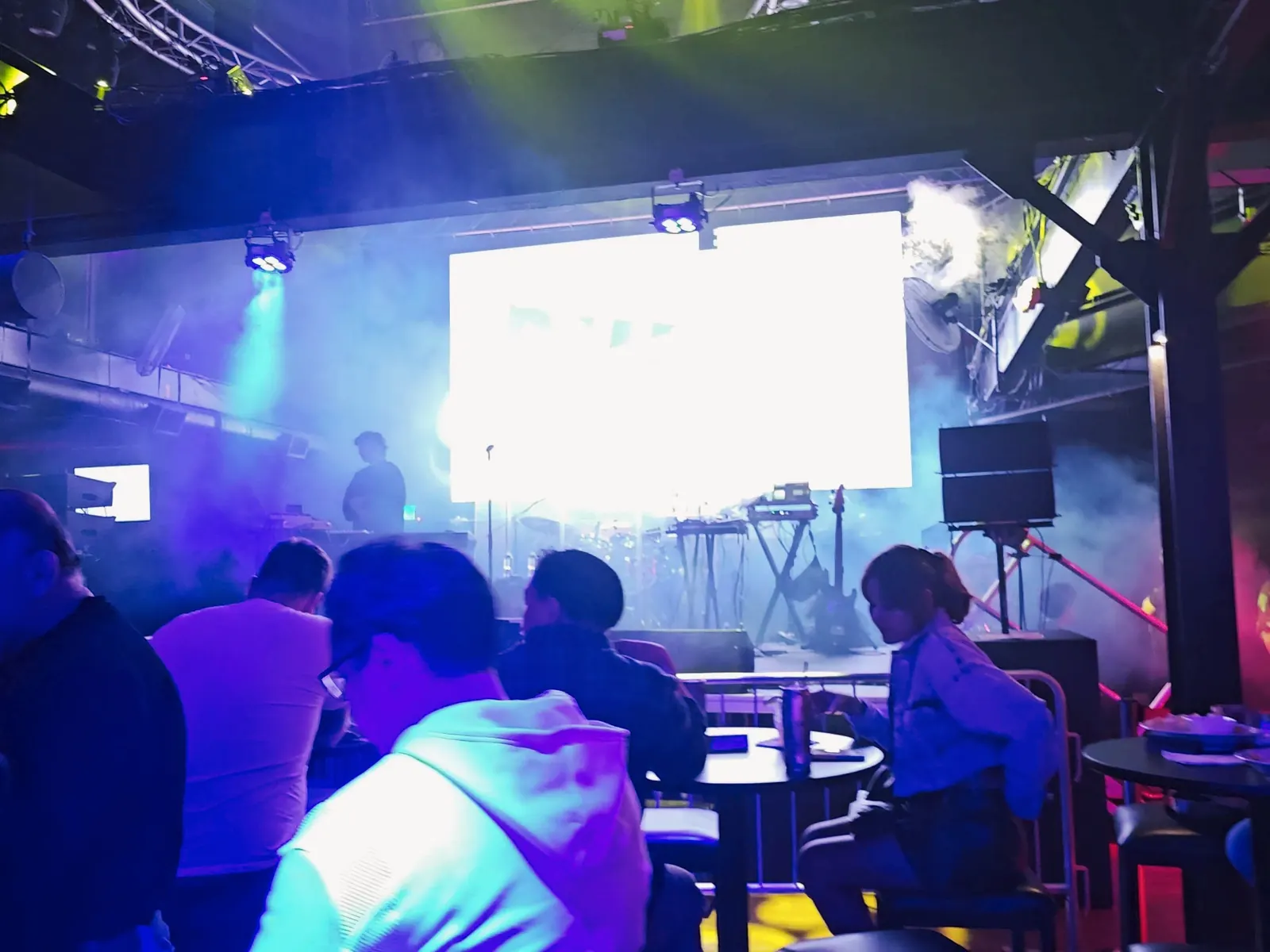 Stage with screen and coloured lights above seated guests at The Salsa Room, Washington