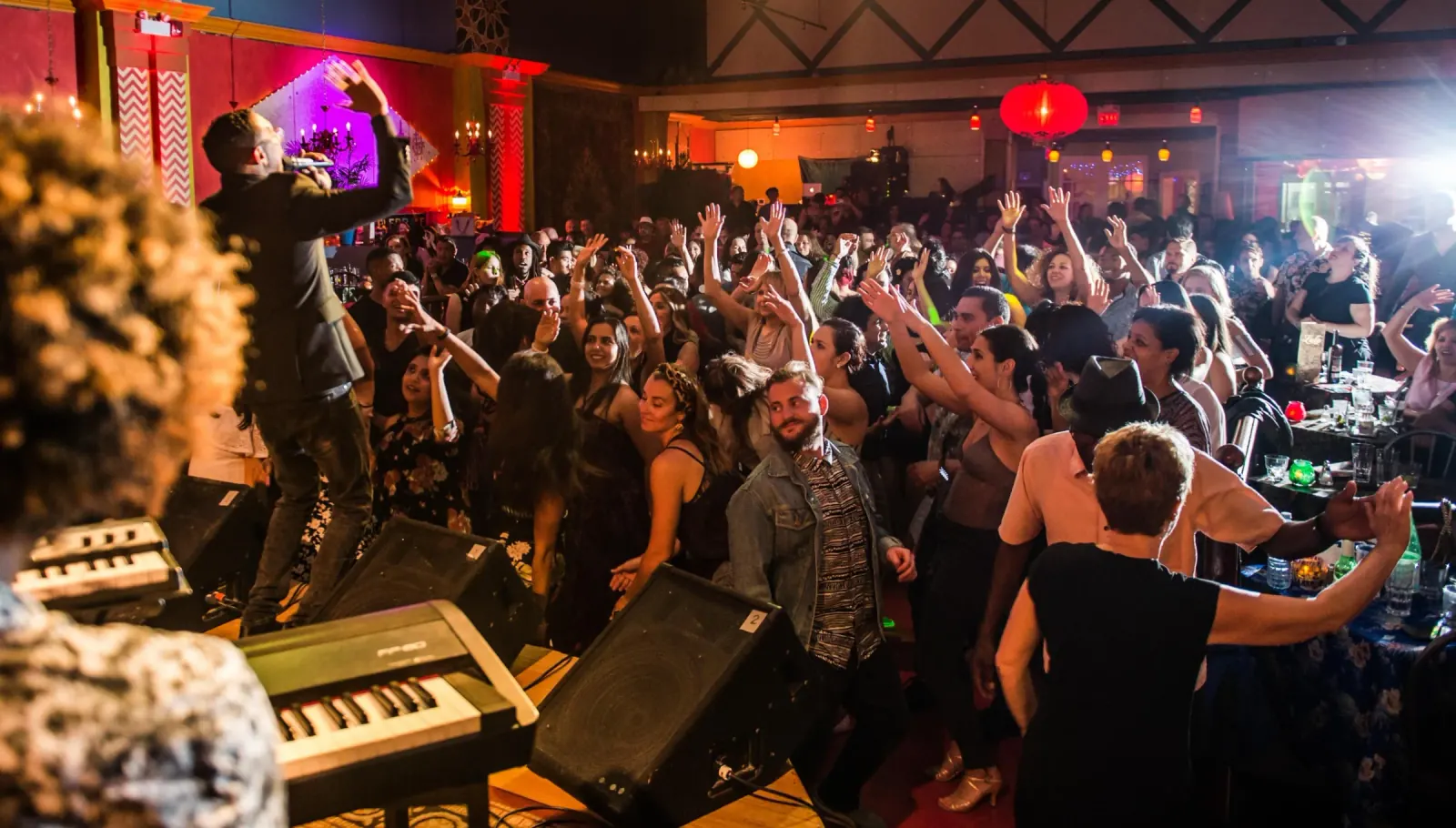 Live music night at Lula Lounge in Toronto, packed crowd enjoying a performance with the stage and colorful venue interior visible