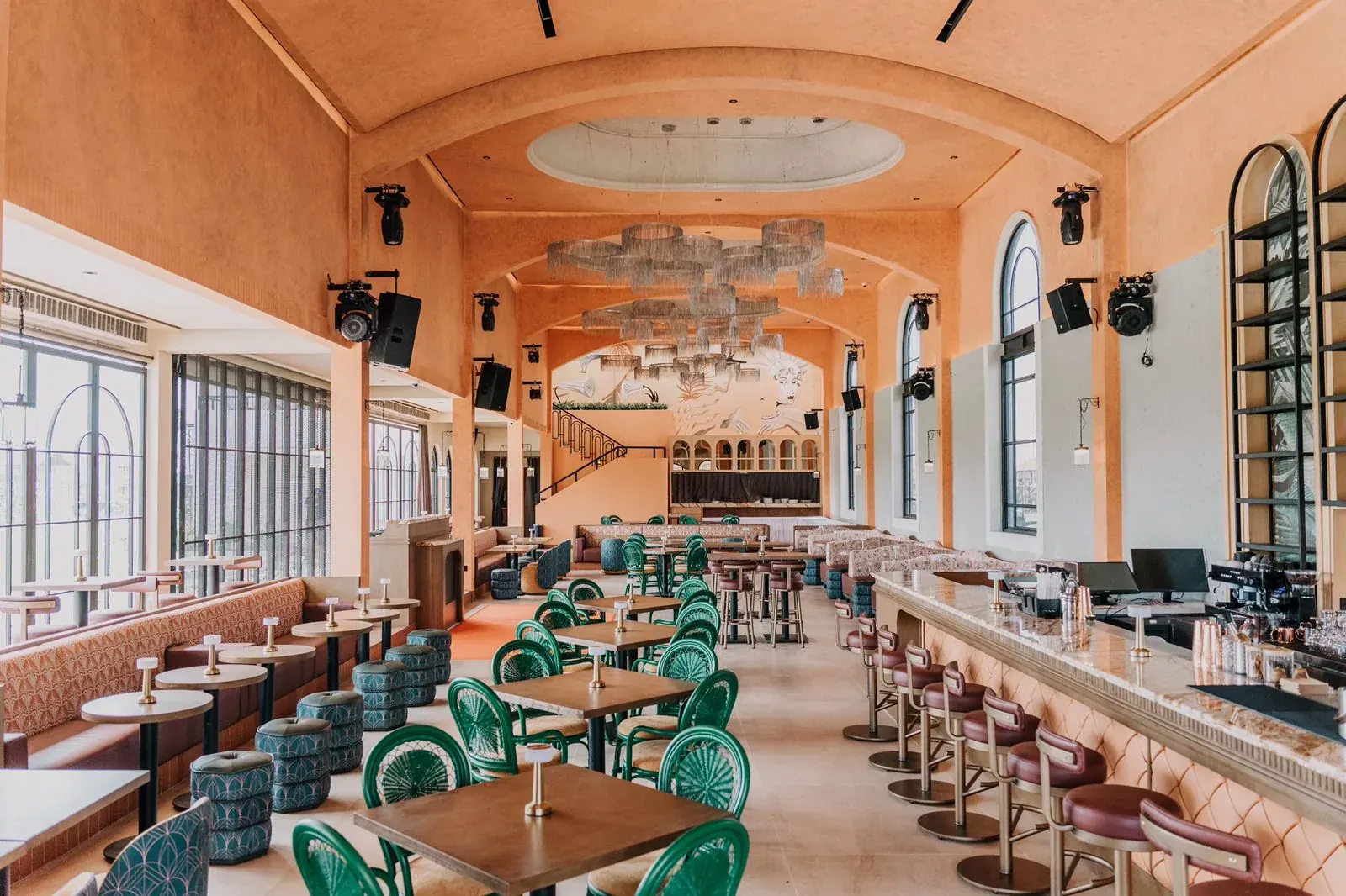 Coral-walled dining hall with chandeliers and bar at Amavi venue in Canggu, Bali
