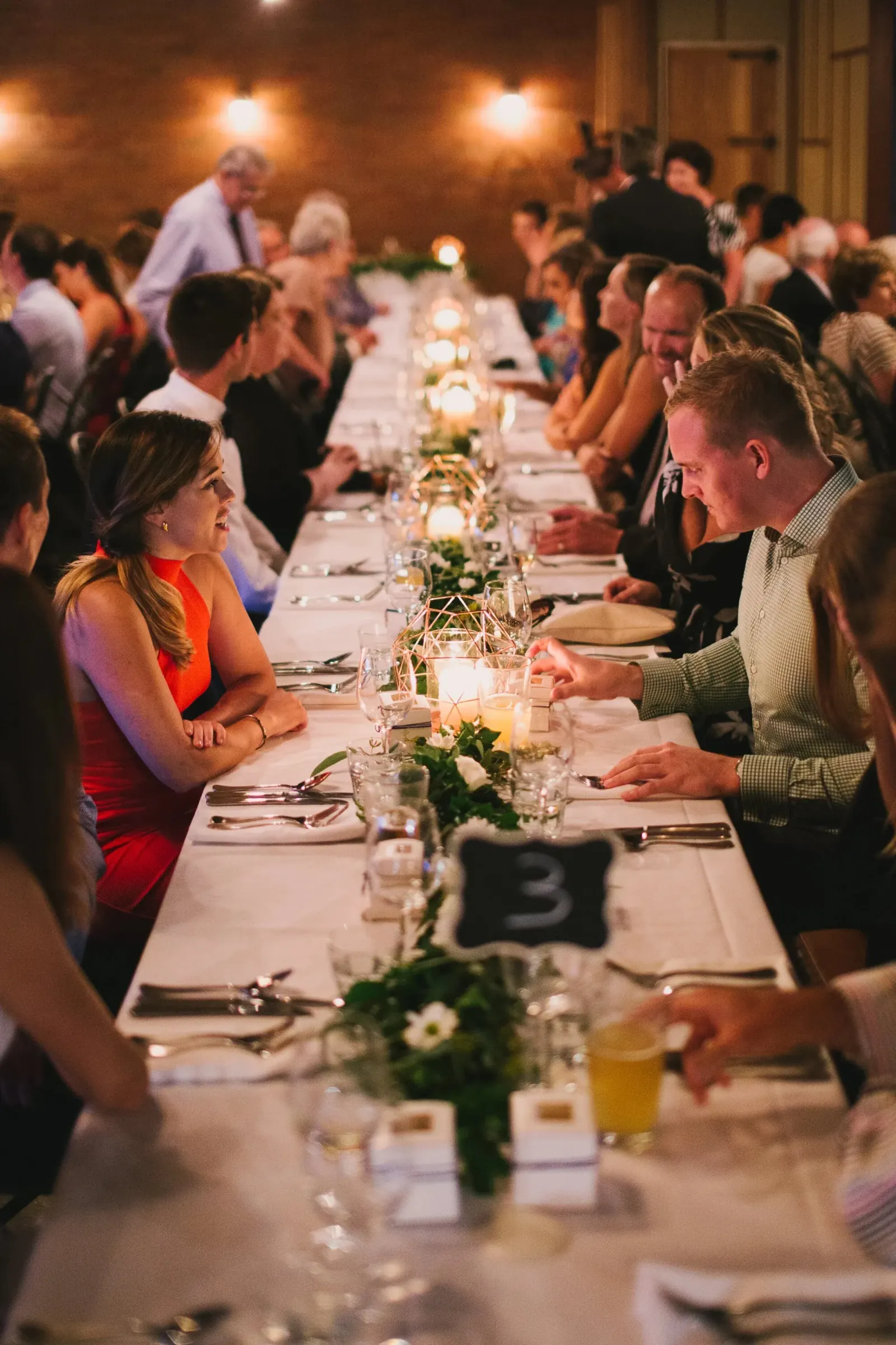 Guests seated and chatting along a candle-lit banquet table during an evening event at Loft West End, Brisbane.