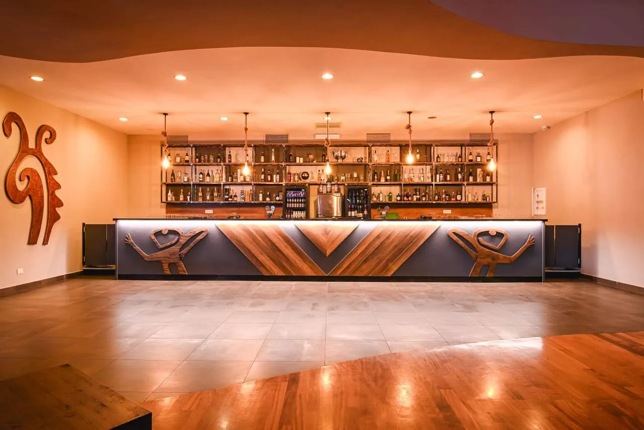 Long bar with dance-figure carvings facing the wooden dance floor at Barrio Latino Rome
