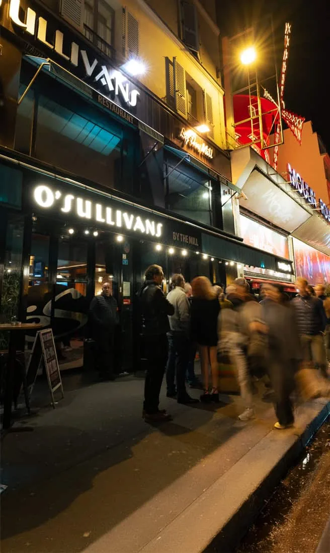 O'Sullivans By The Mill in Pigalle Paris, the SalsaO'Sulli venue, with crowd outside at night near Moulin Rouge