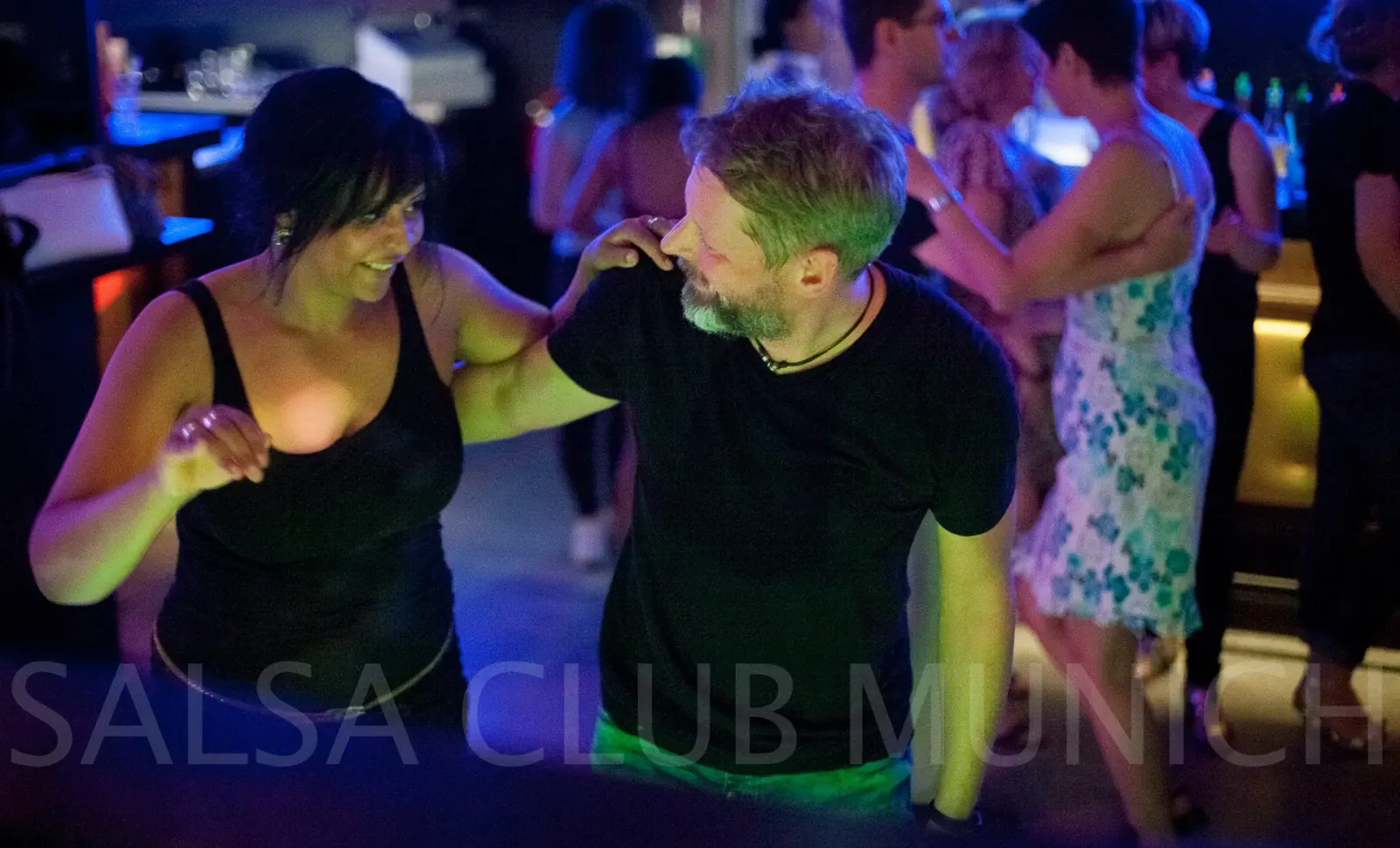 Salsa partner dance under green and blue club lights at Salsa Club Munich