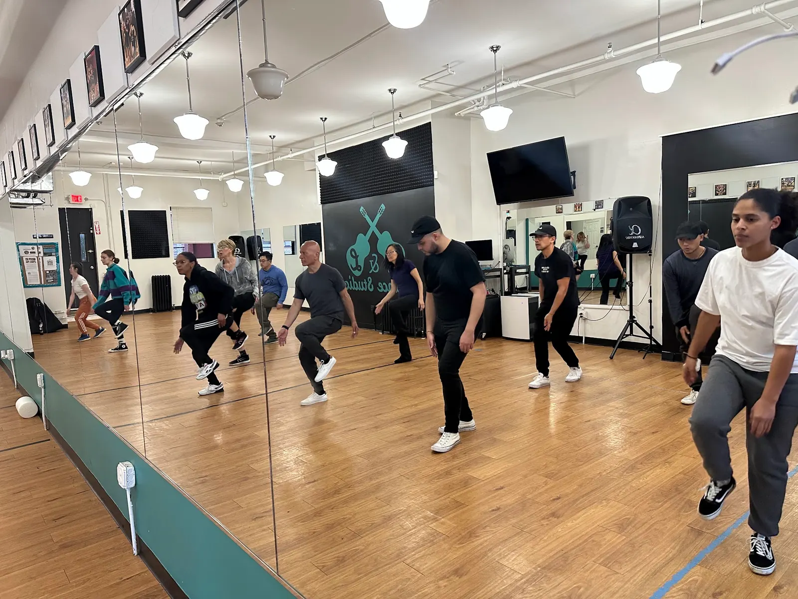 Dancers following a step on the wooden floor at J&L Dance Studio in Boston beside the mirror wall