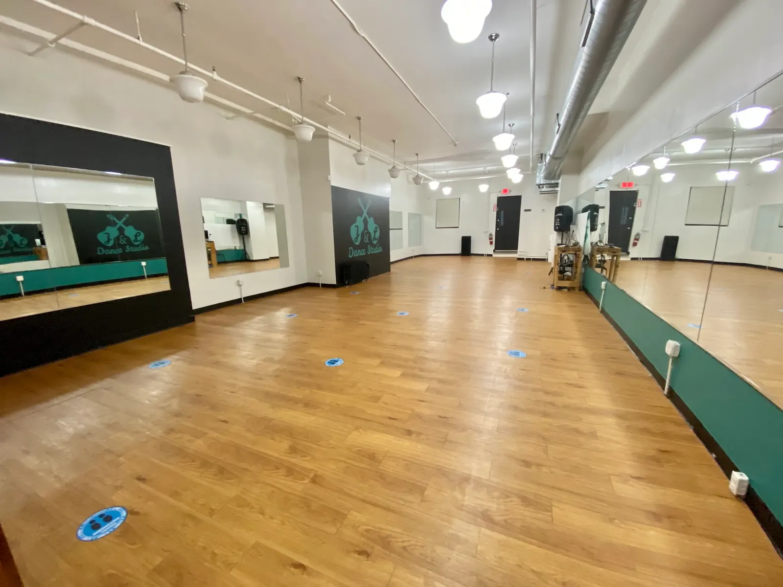 Empty wooden dance floor with mirror walls and the J&L Dance Studio logo on the wall in Boston