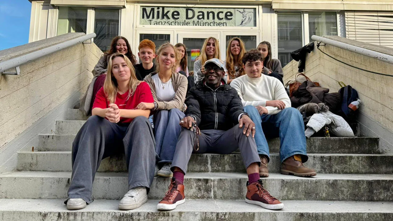 Group of dancers at the Mike Dance Tanzschule entrance with branded signage in Munich