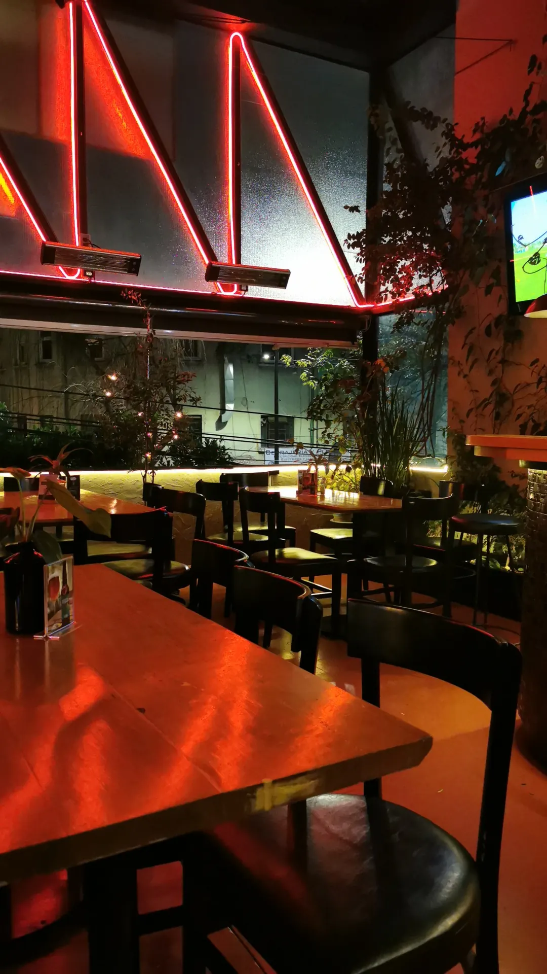 Empty terrace at La Terraza Michoacan 78 in Mexico City lit by red neon with heaters overhead