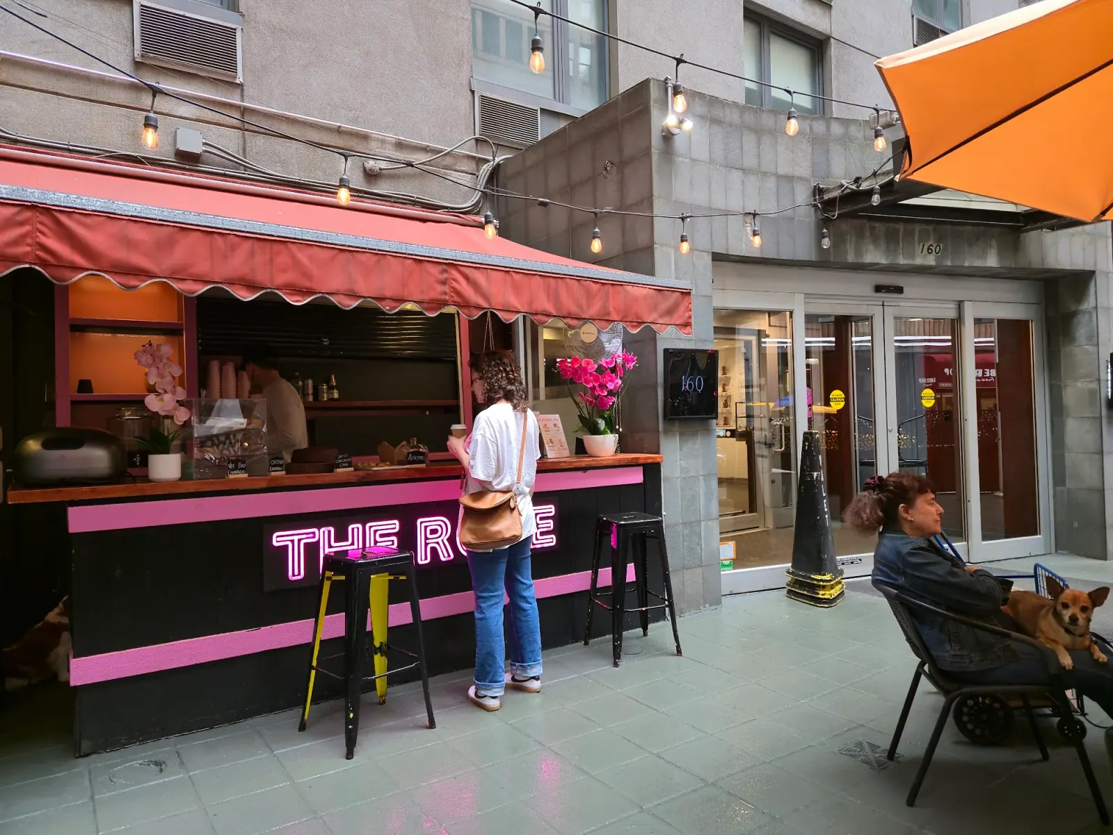 The Rose NYC patio entrance with customers and pink neon signage in New York