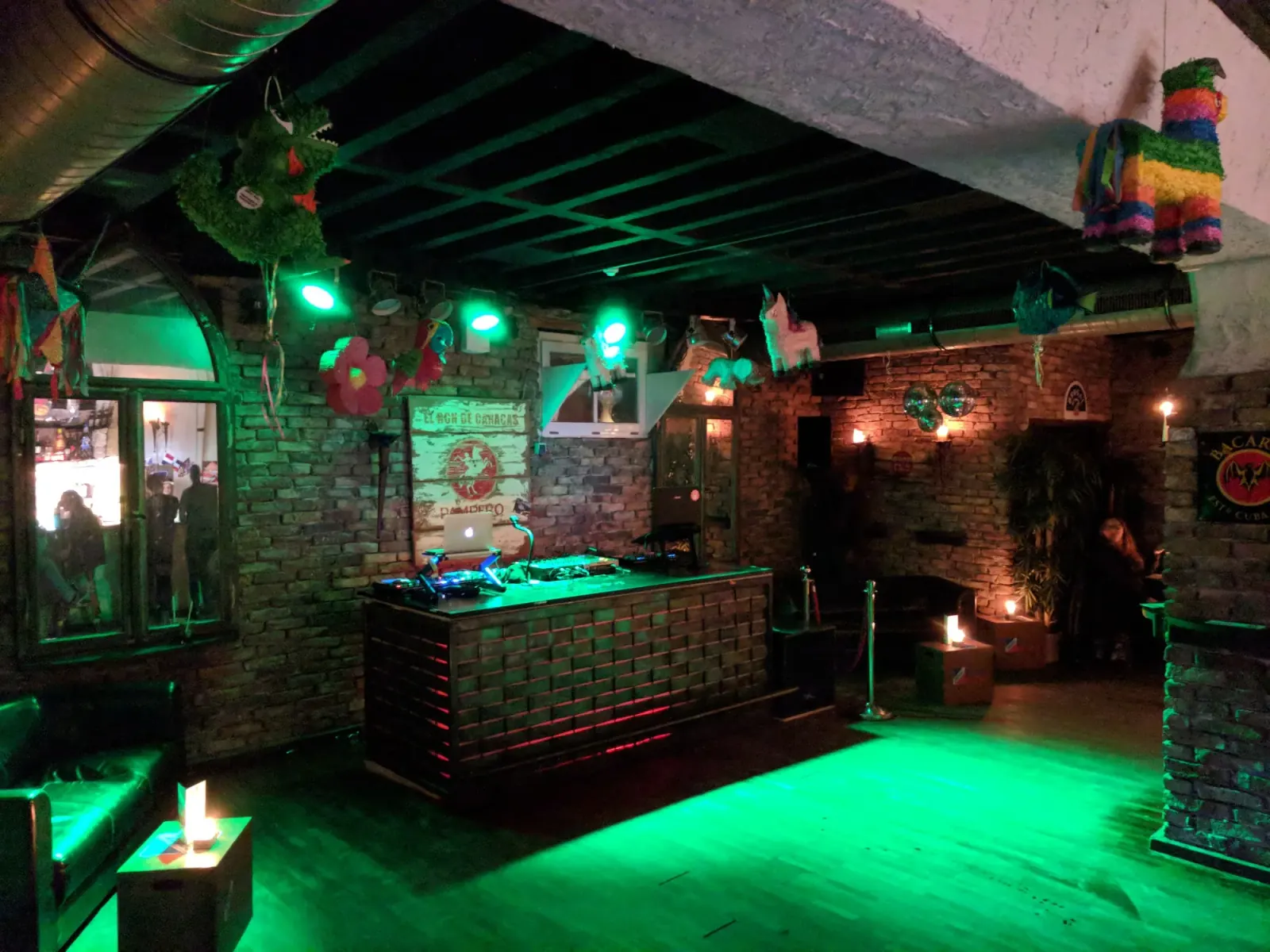 DJ booth with green dance floor and pinata decorations at Club Fogon Nuremberg