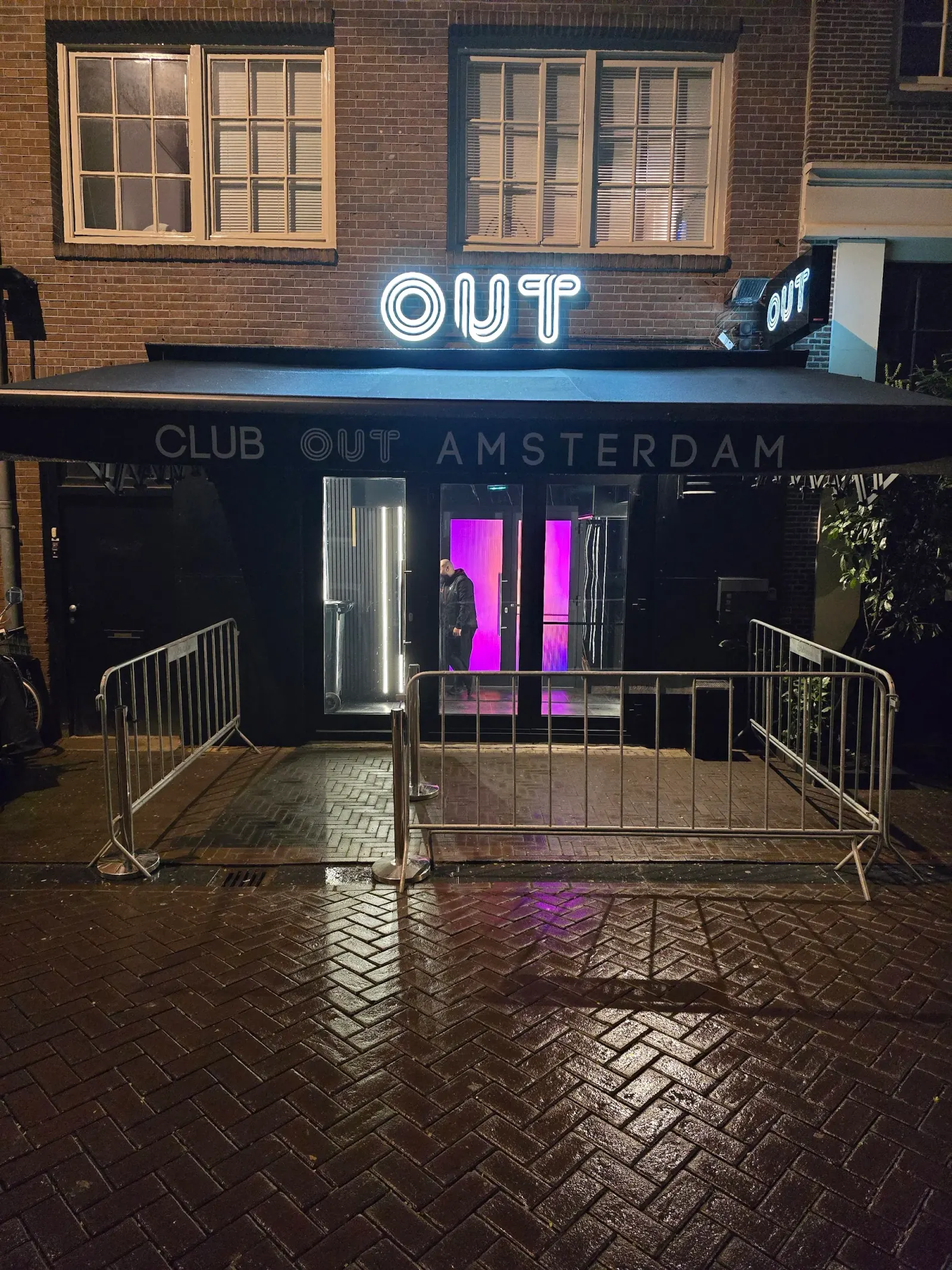 OUT Latin Club Amsterdam exterior at night — Club Out Amsterdam neon sign glowing purple above entrance