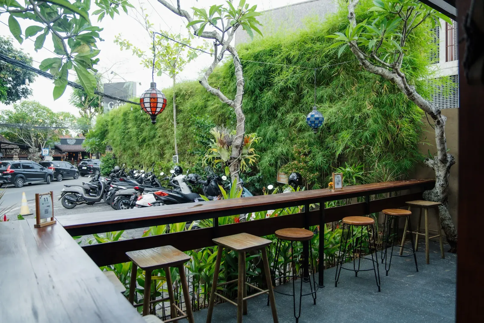 Outdoor bar counter and seating at Pilleyar Bar & Kitchen Bali with lush greenery and lanterns