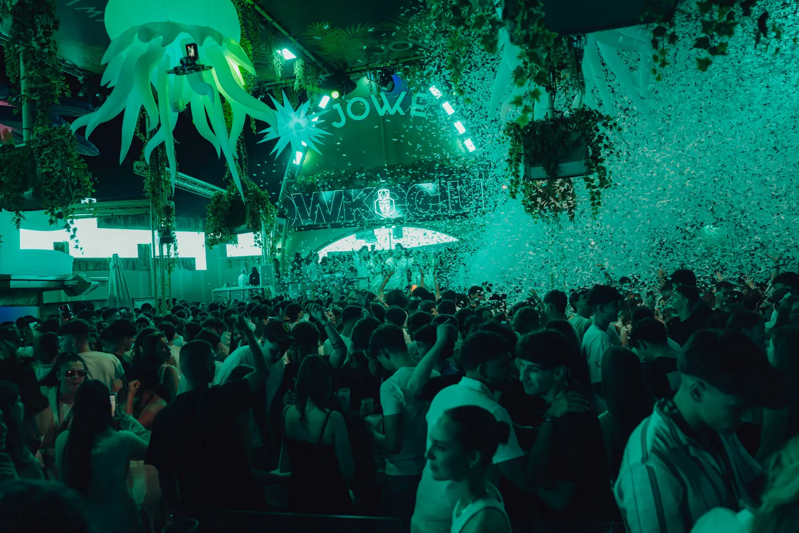 Lively crowd dancing under green lights and the illuminated Jowke sign, Alcorcon
