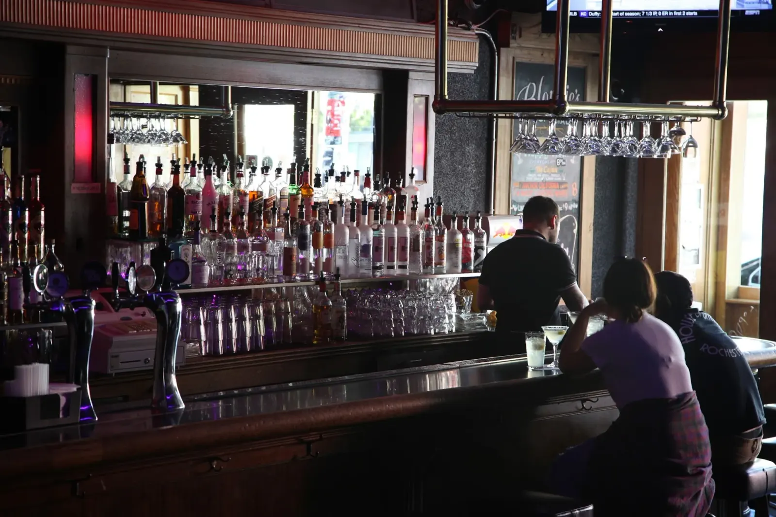 Wide view of the long backbar and bottle wall inside Blondie's Bar San Francisco with patrons at the counter