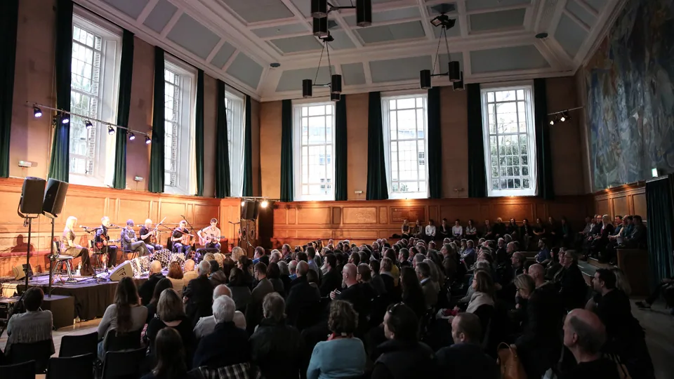 Kennedy Hall interior at Cecil Sharp House, London showing a live music performance with seated audience in the grand wood-paneled hall