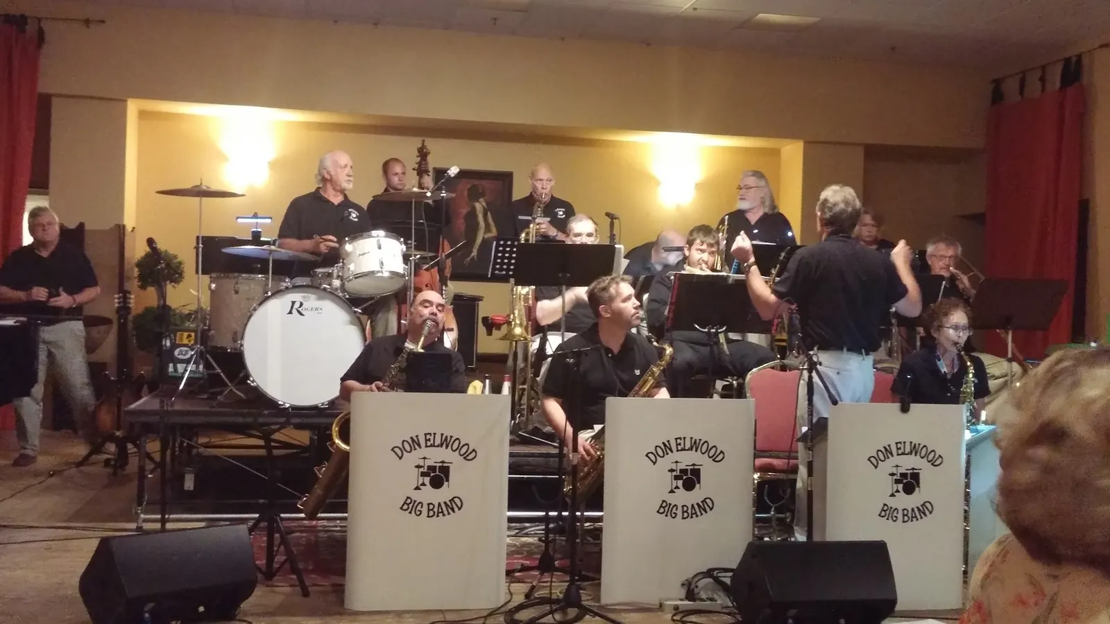 Big band playing beside the red stage curtains in the hall at The Avalon Ballroom