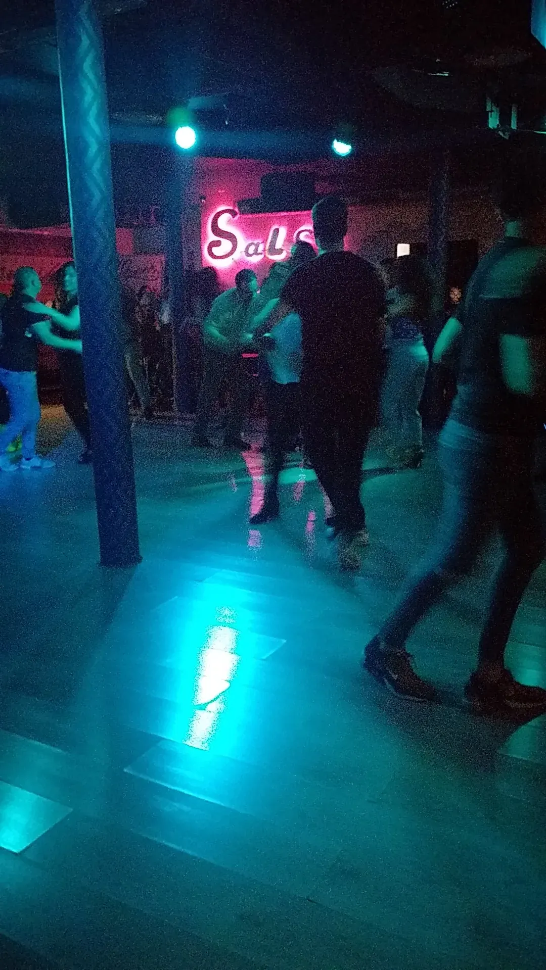 Couple dancing salsa with neon sign in background at Sala Muévete Málaga