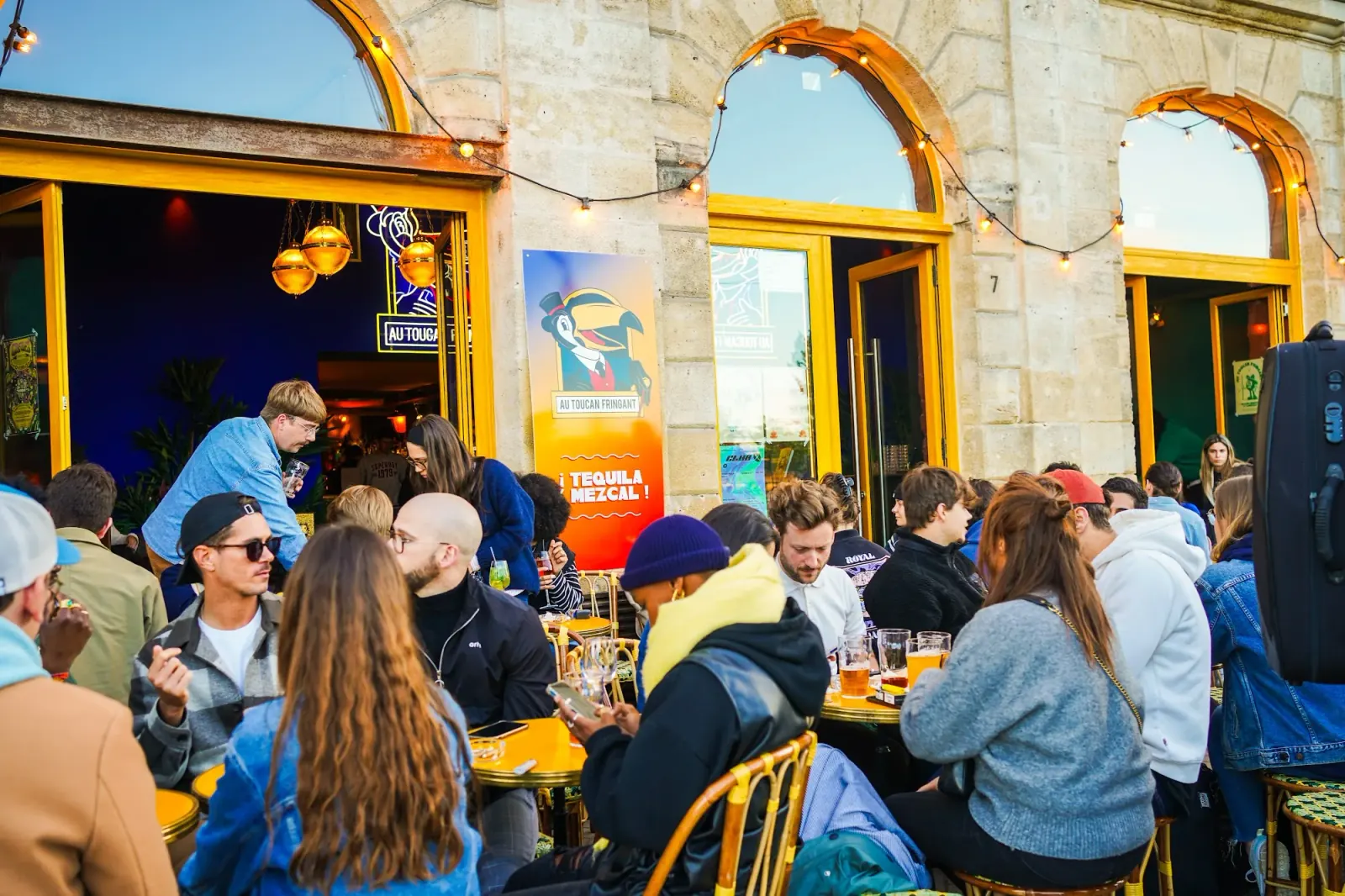 Lively outdoor patio crowd at Toucan Fringuant tropical bar in Bordeaux