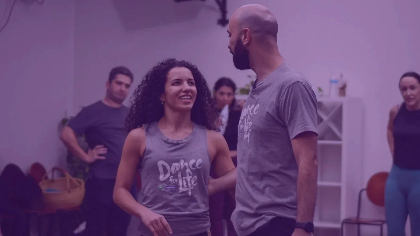 Dance instructors wearing Dance for Life shirts demonstrating partner work at Rio Rhythmics Latin Dance Academy in Brisbane