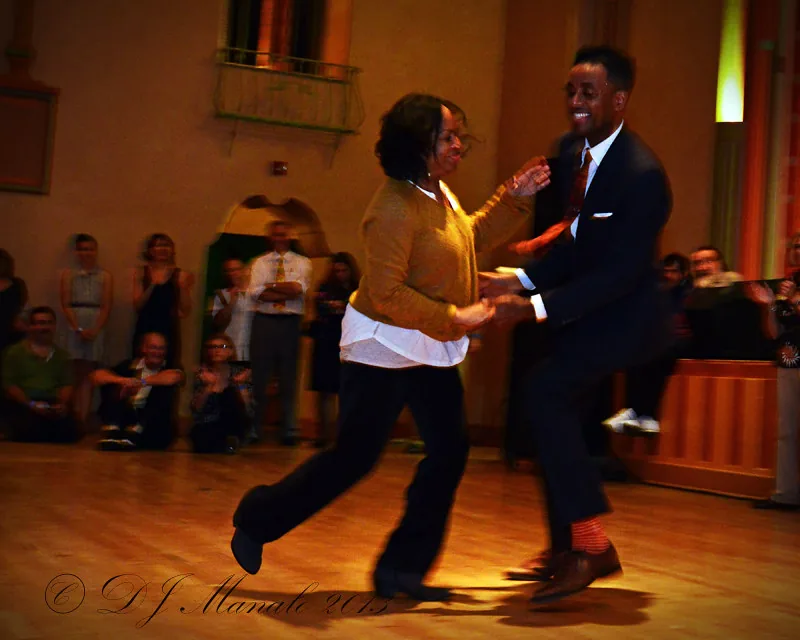 Dance couple performing on the wooden ballroom floor at Glen Echo Park in Washington D.C. with audience watching