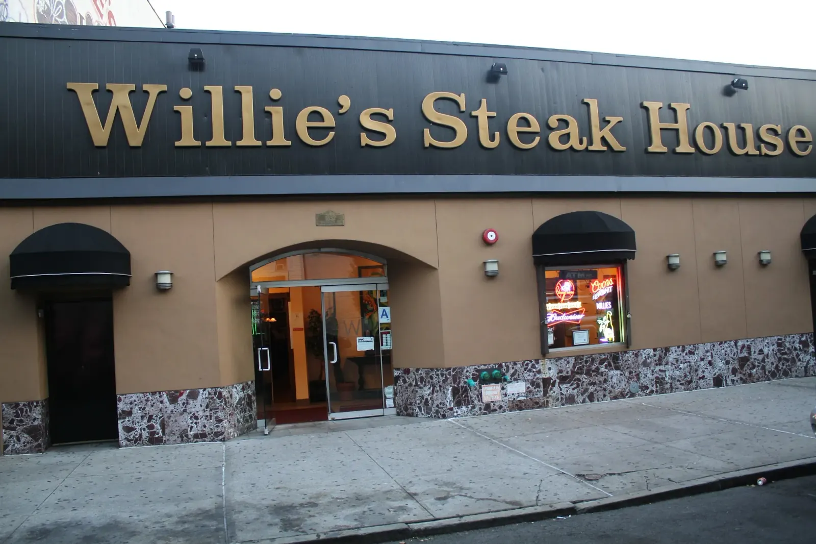 Willie's Steak House full storefront entrance with gold signage and neon window display, Bronx New York