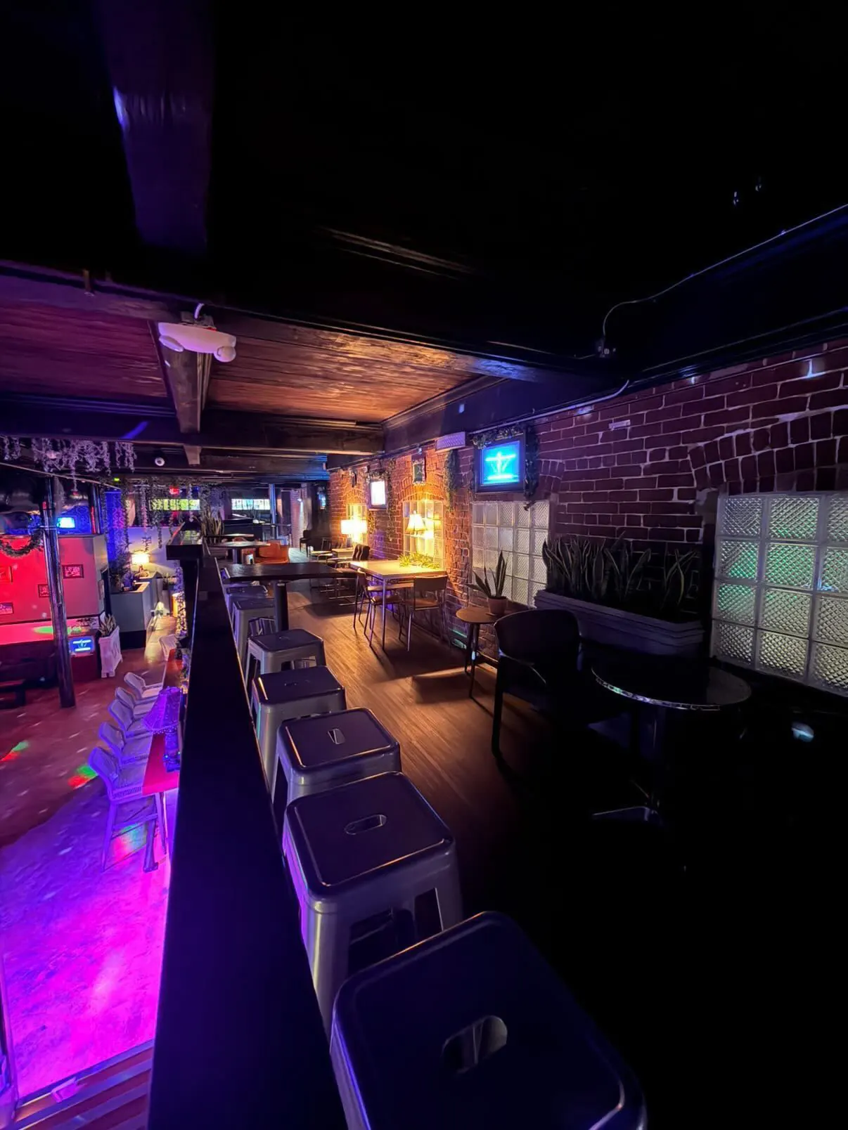 Bar rail and stools beside the lit dance floor inside Distrito Federal in Houston