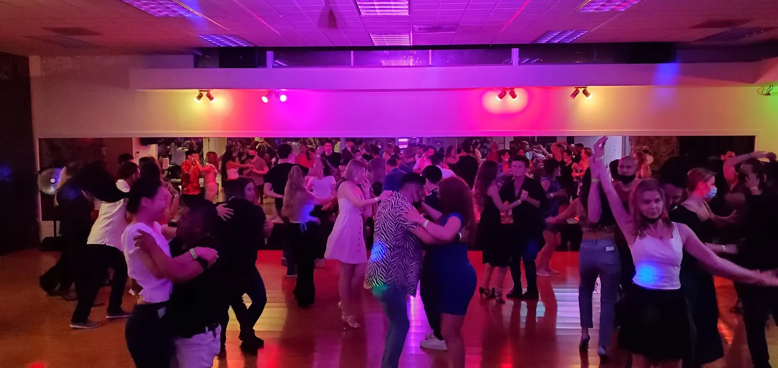 Packed dance floor with dozens of dancers under coloured lights at Dance Boulevard
