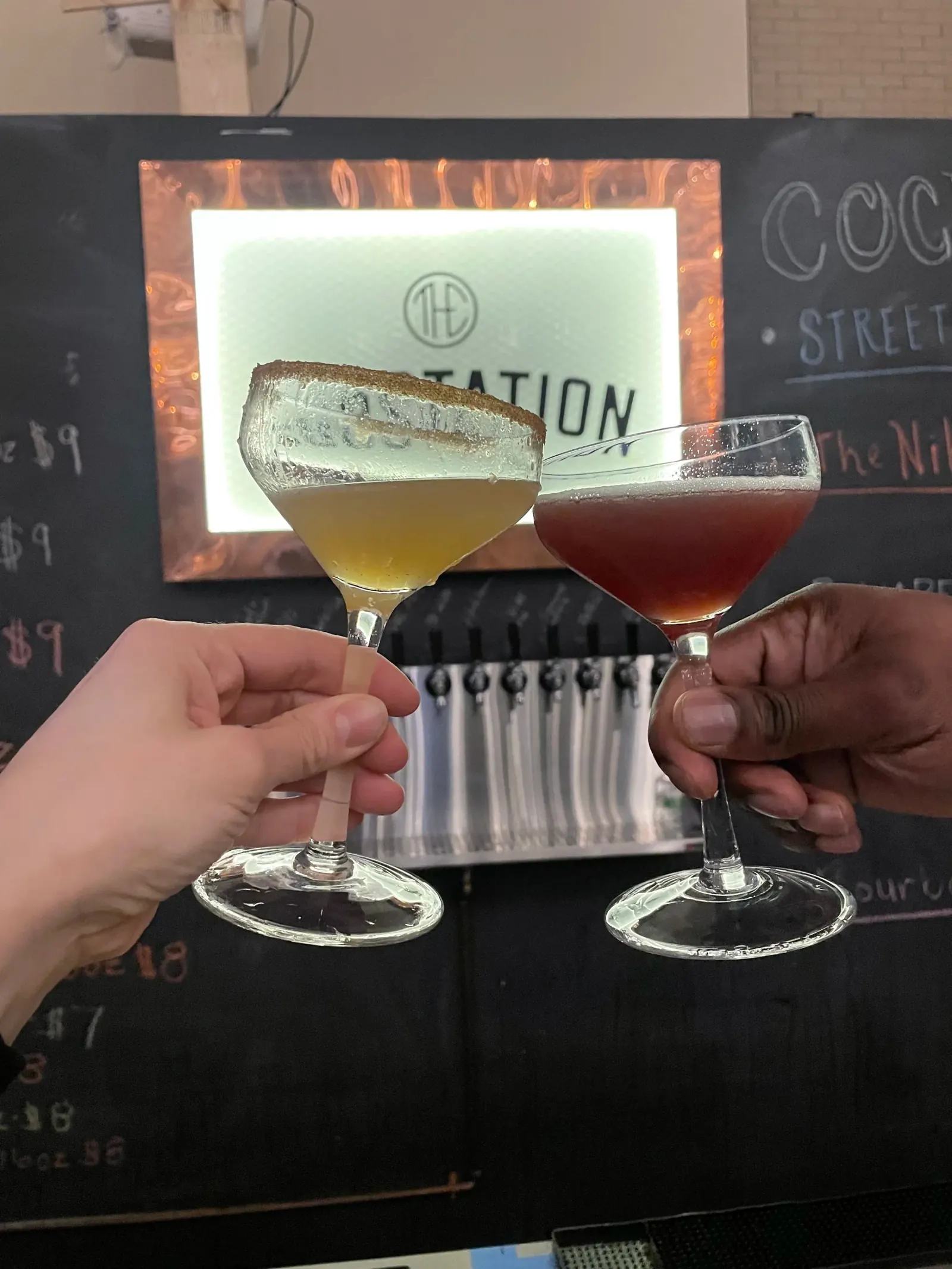 Cocktails toasted in front of the illuminated Substation bar sign in Boston