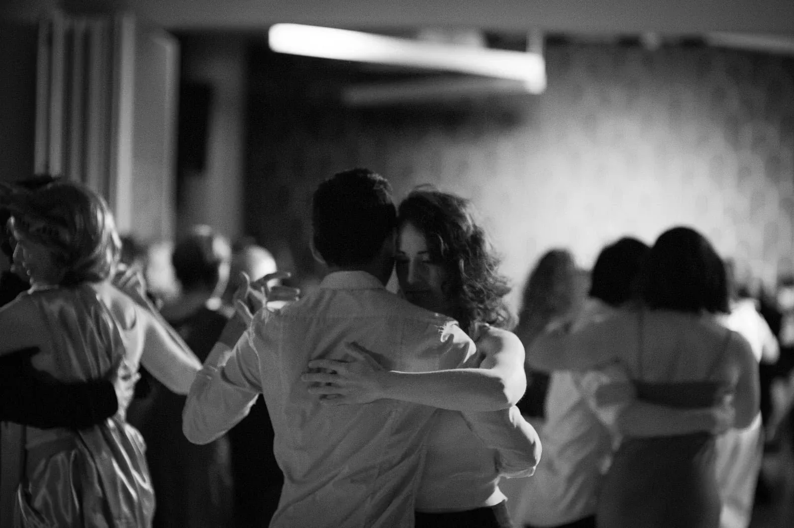 Couples enjoying social dancing at You Should Be Dancing in New York, captured in an atmospheric black and white photograph showing multiple pairs on the dance floor