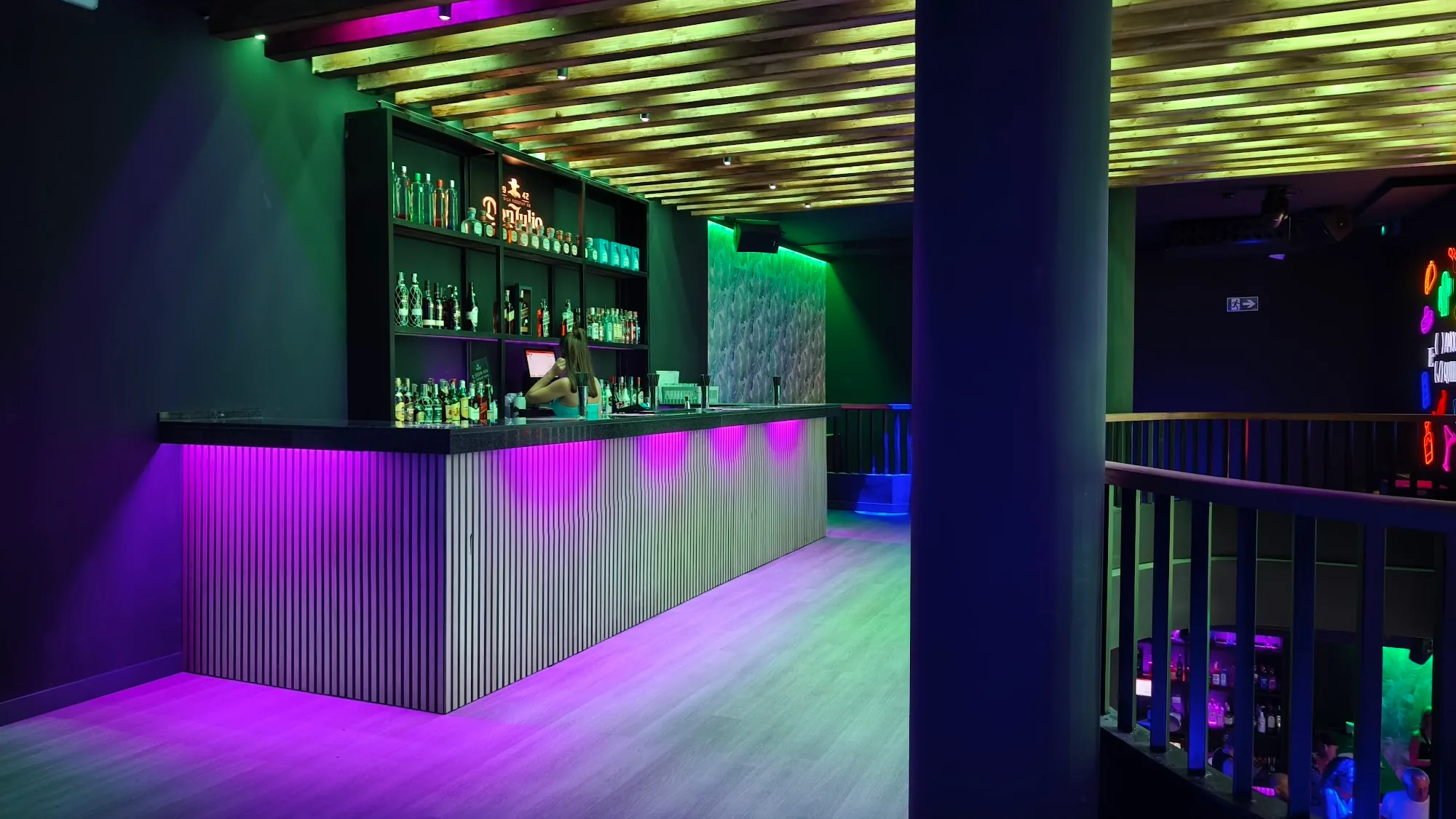 Bar with purple and green neon lighting and dance floor at Antilla Salsa, Barcelona