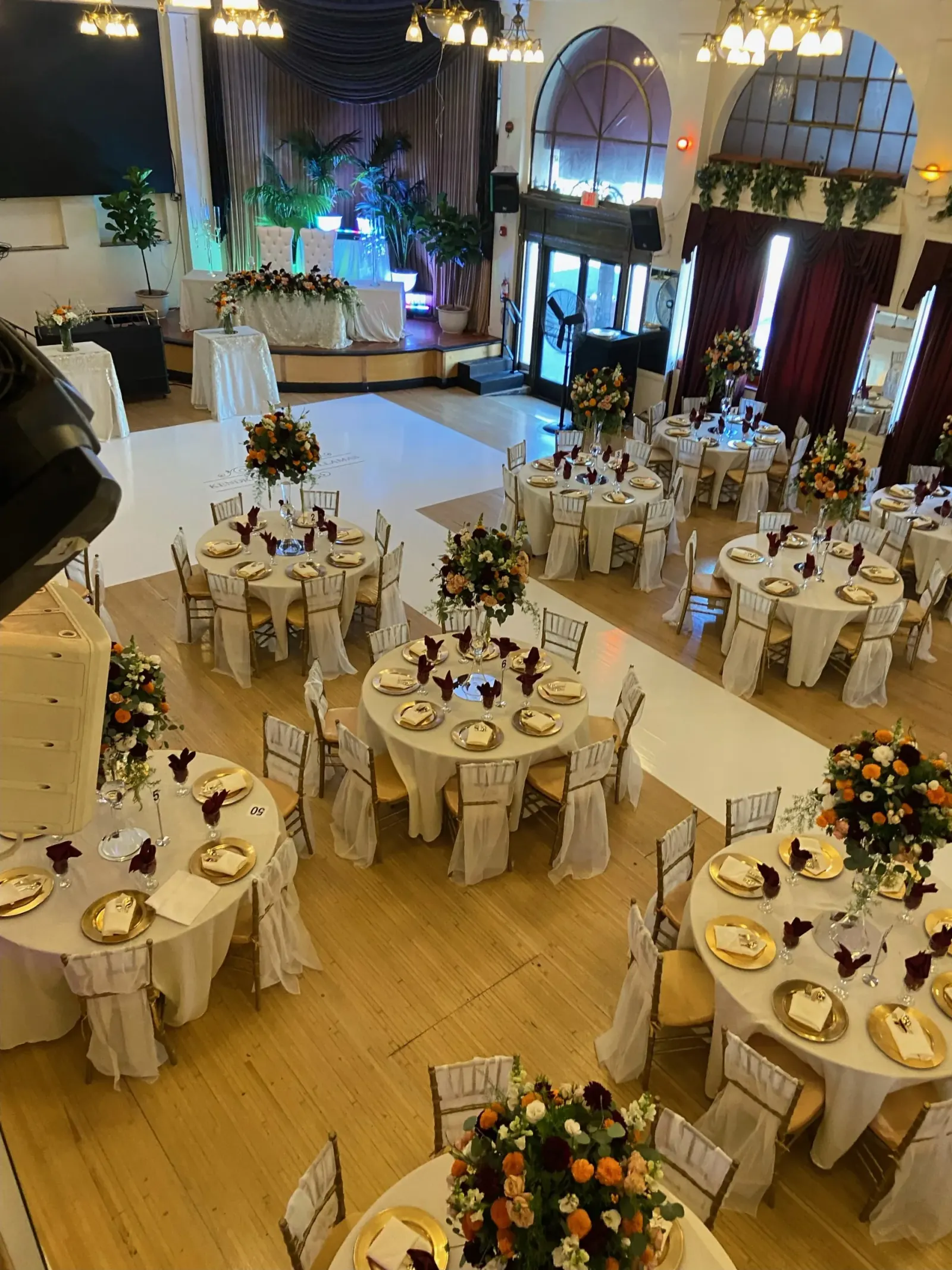Interior ballroom set with round banquet tables, chandeliers and a stage beside the dance floor at The Granada LA, Los Angeles