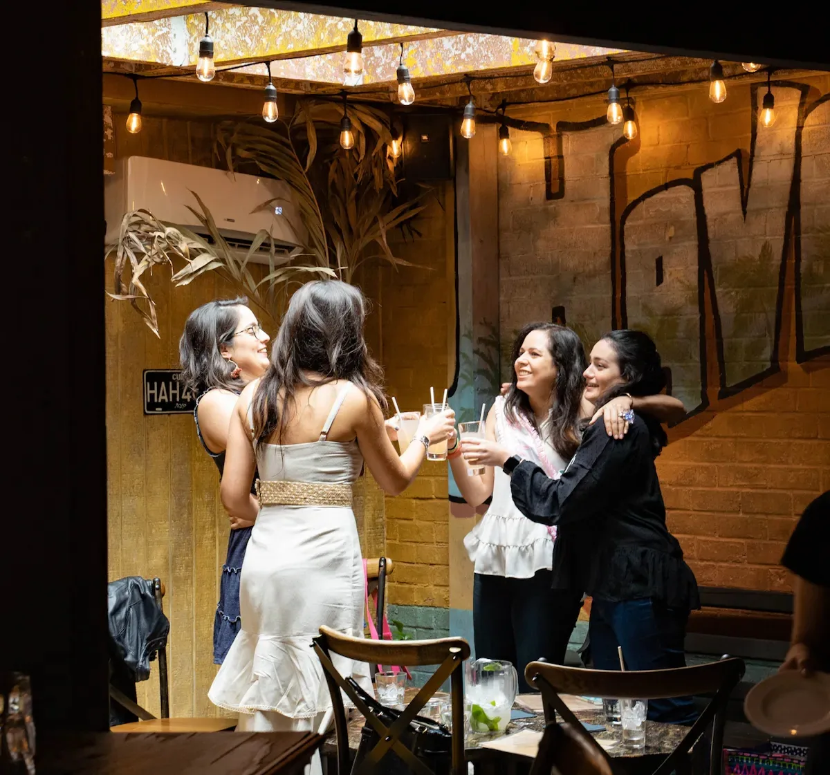 Friends toasting drinks under string lights inside Casta’s Rum Bar in Washington DC