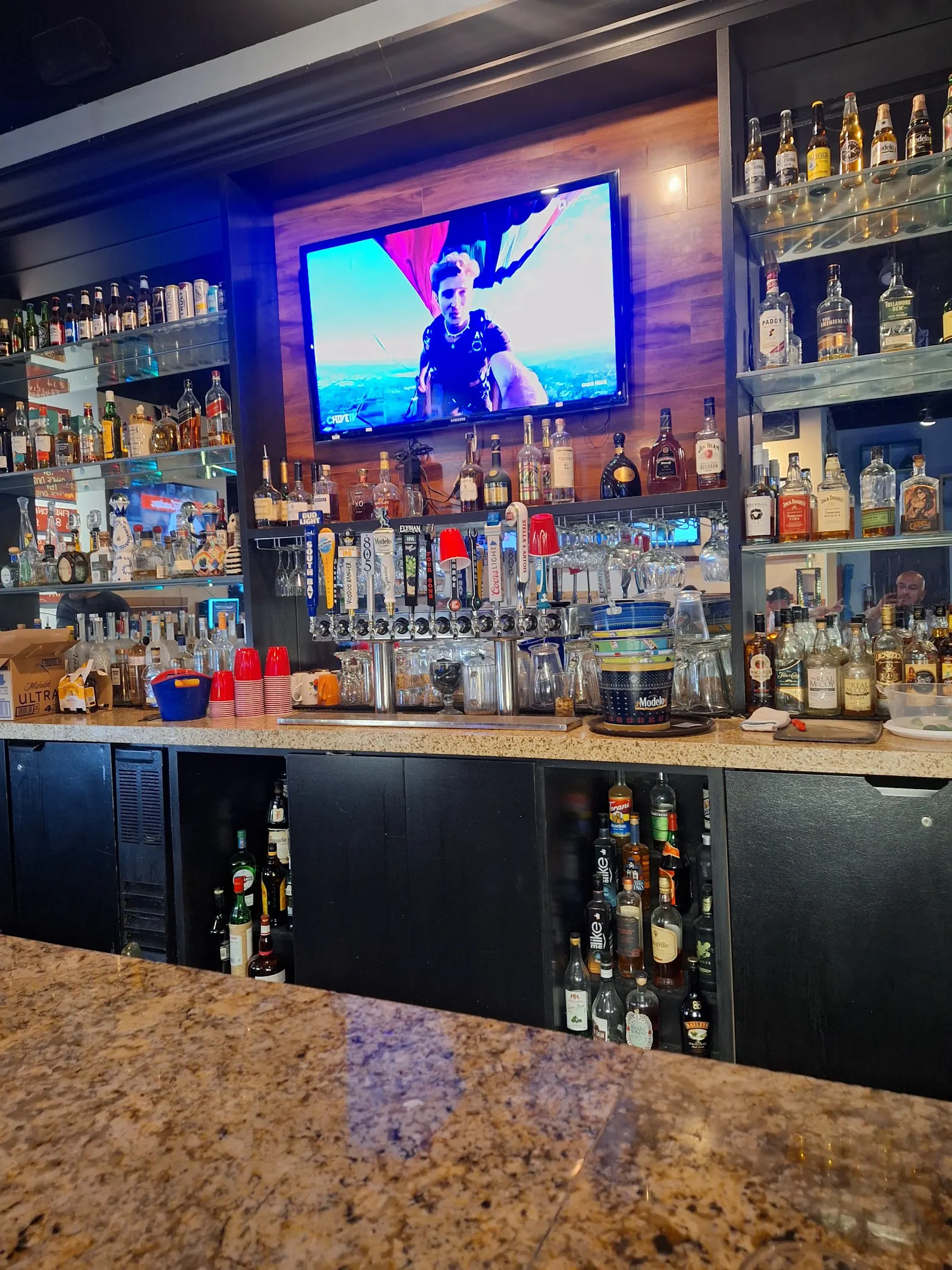 Bar counter with spirit shelves and a screen inside Schooner Bar & Grill, Los Angeles