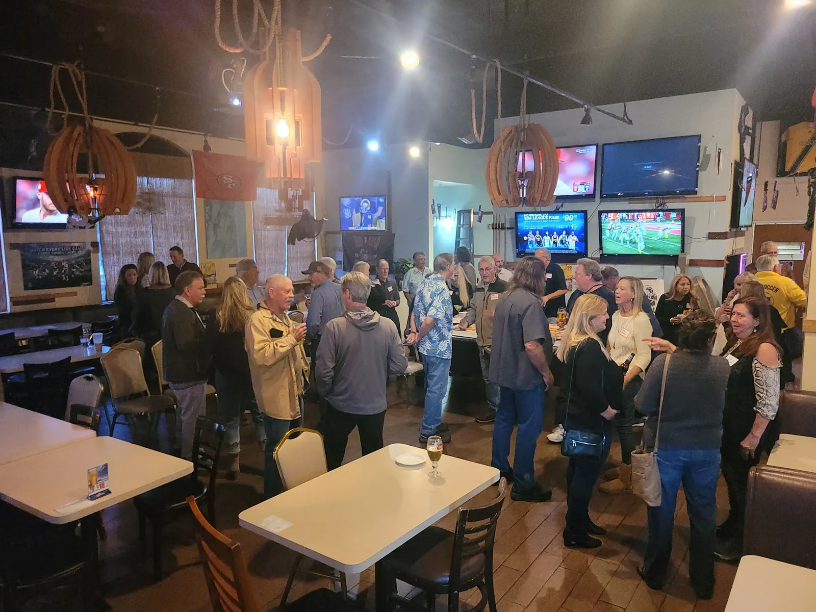 Guests standing between tables and screens inside Schooner Bar & Grill, Los Angeles