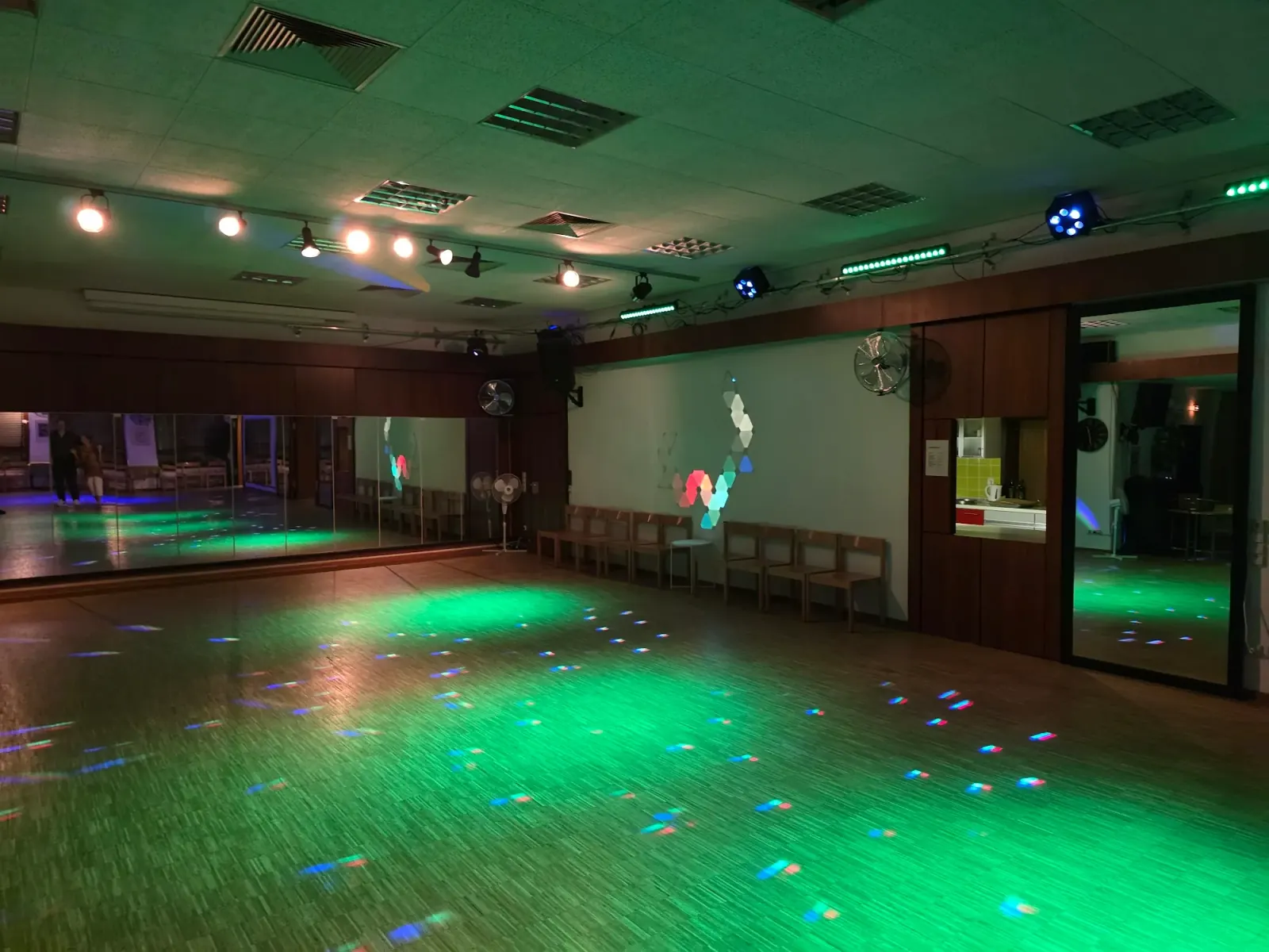 Green-lit dance studio with mirrors and stage lighting at Tanzschule Wilfego in Nuremberg