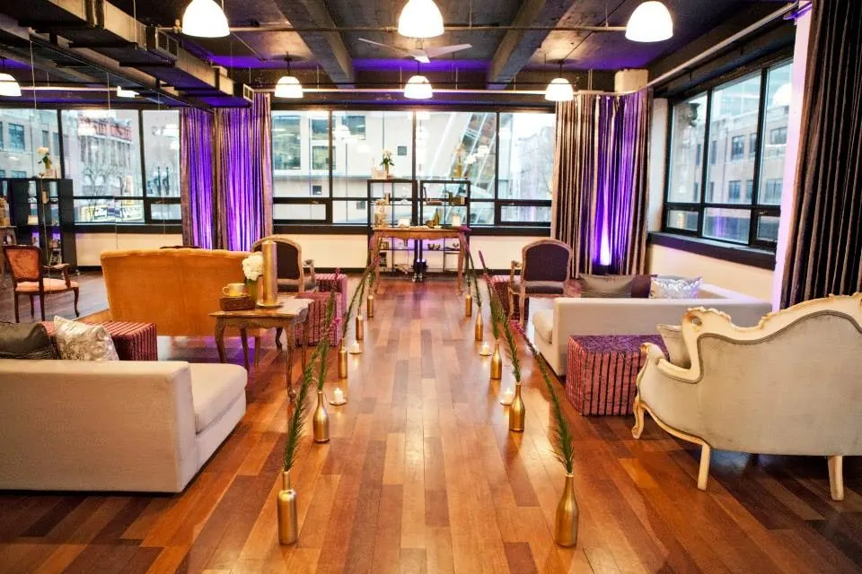 Lounge seating on the wooden floor with purple lit curtains at Espaces des Arts